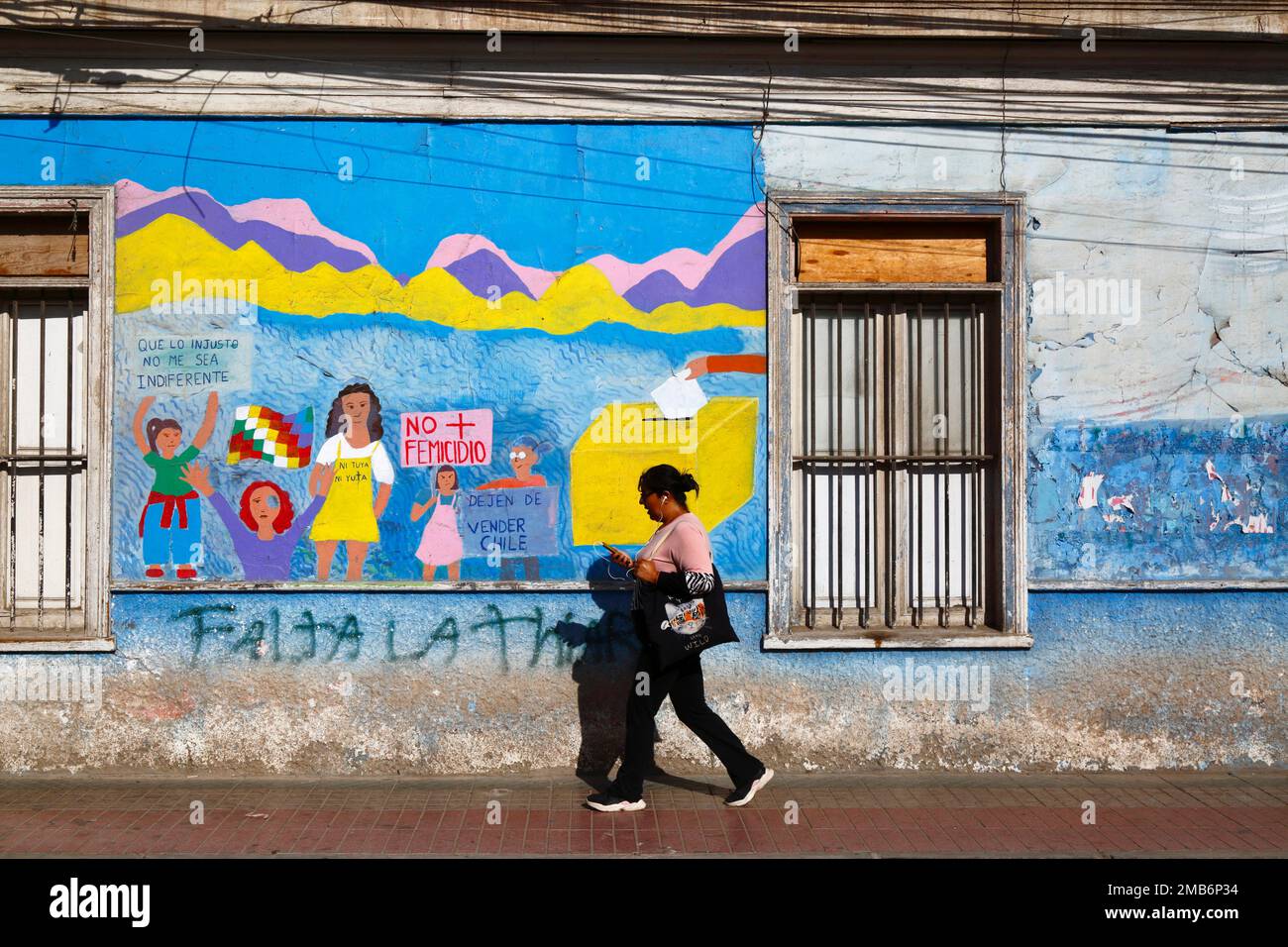 Woman walking past mural on wall of school protesting against violence against women and demanding equal rights for women, Copiapo, Region III, Chile Stock Photo