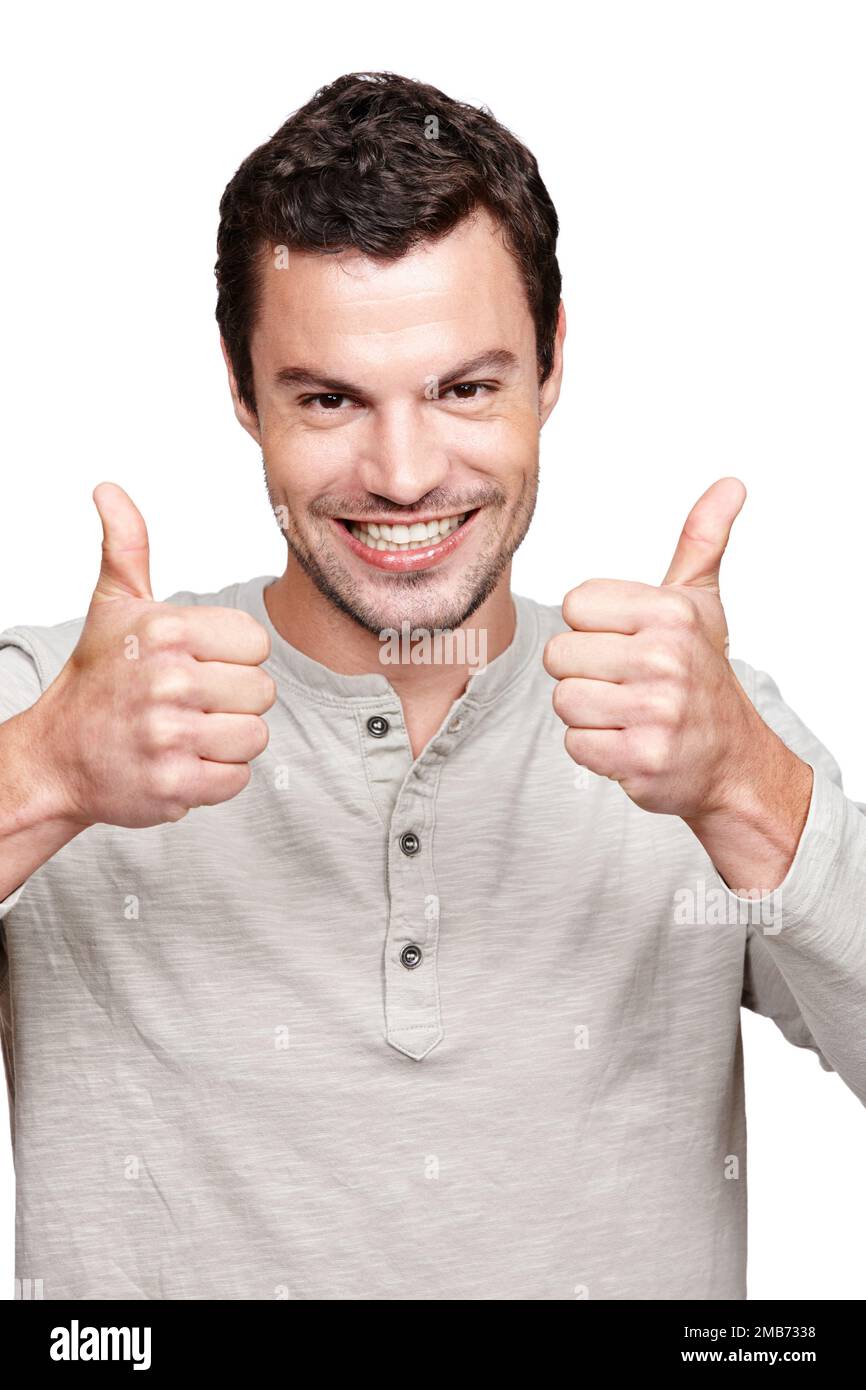 Young man, thumbs up and smile for winning, discount or sale against a white studio background. Portrait of a isolated handsome male giving thumbsup Stock Photo