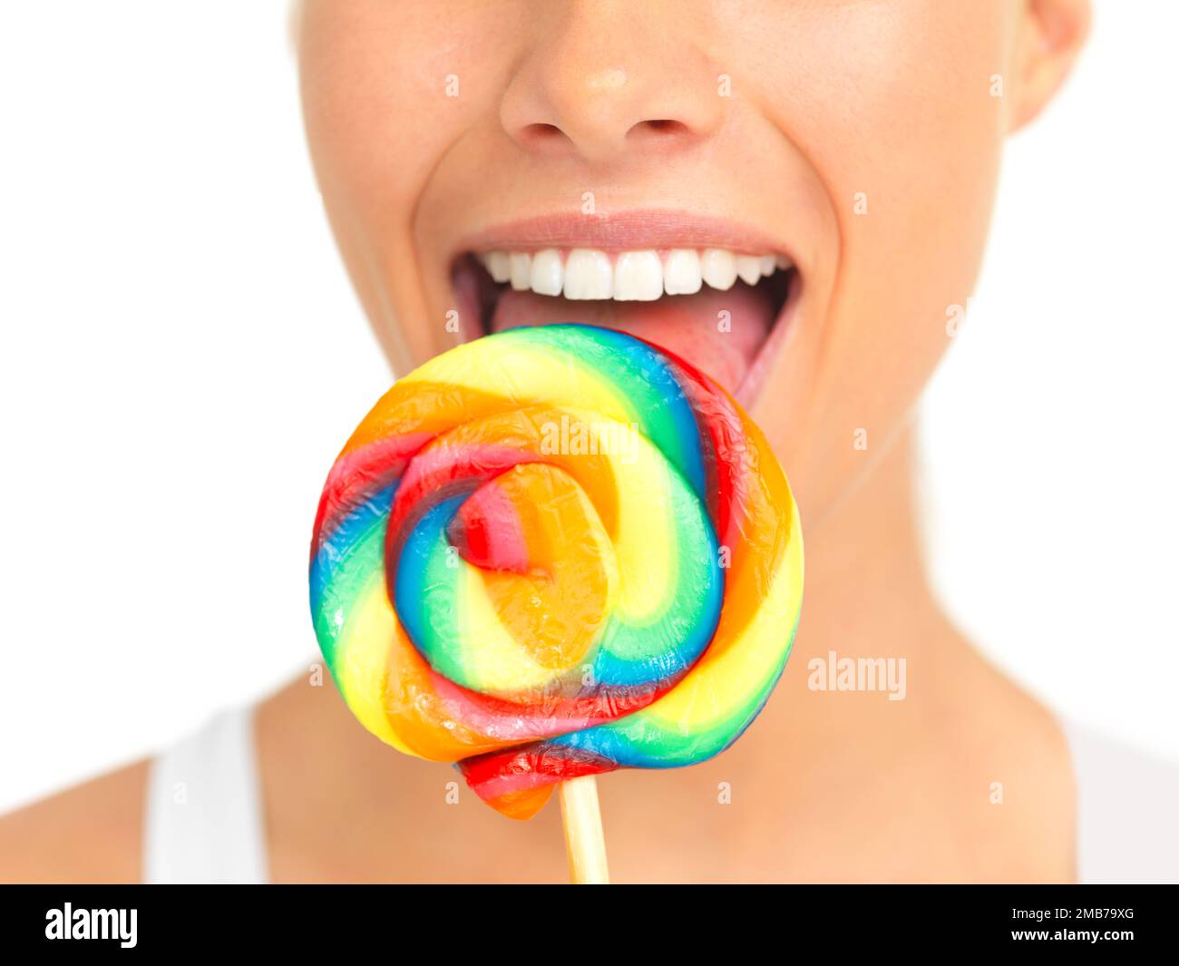 Candy, lollipop and sweets with a woman in studio isolated on a white background eating a sweet snack. Food, bright or color with a young female Stock Photo