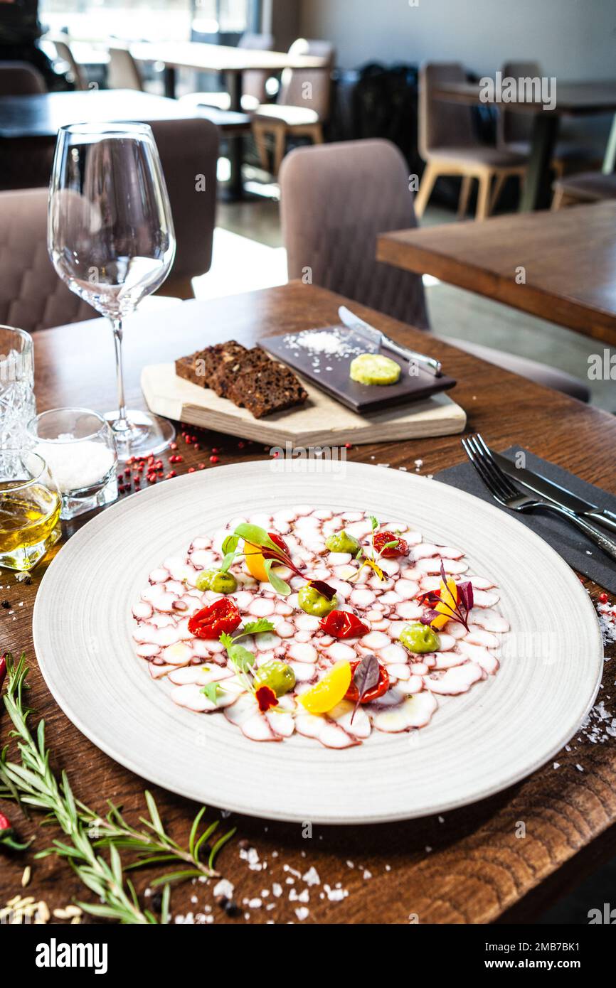 Octopus carpaccio. Spinach cream, cherry tomatoes. Delicious healthy Italian traditional food closeup served for lunch in modern gourmet cuisine Stock Photo