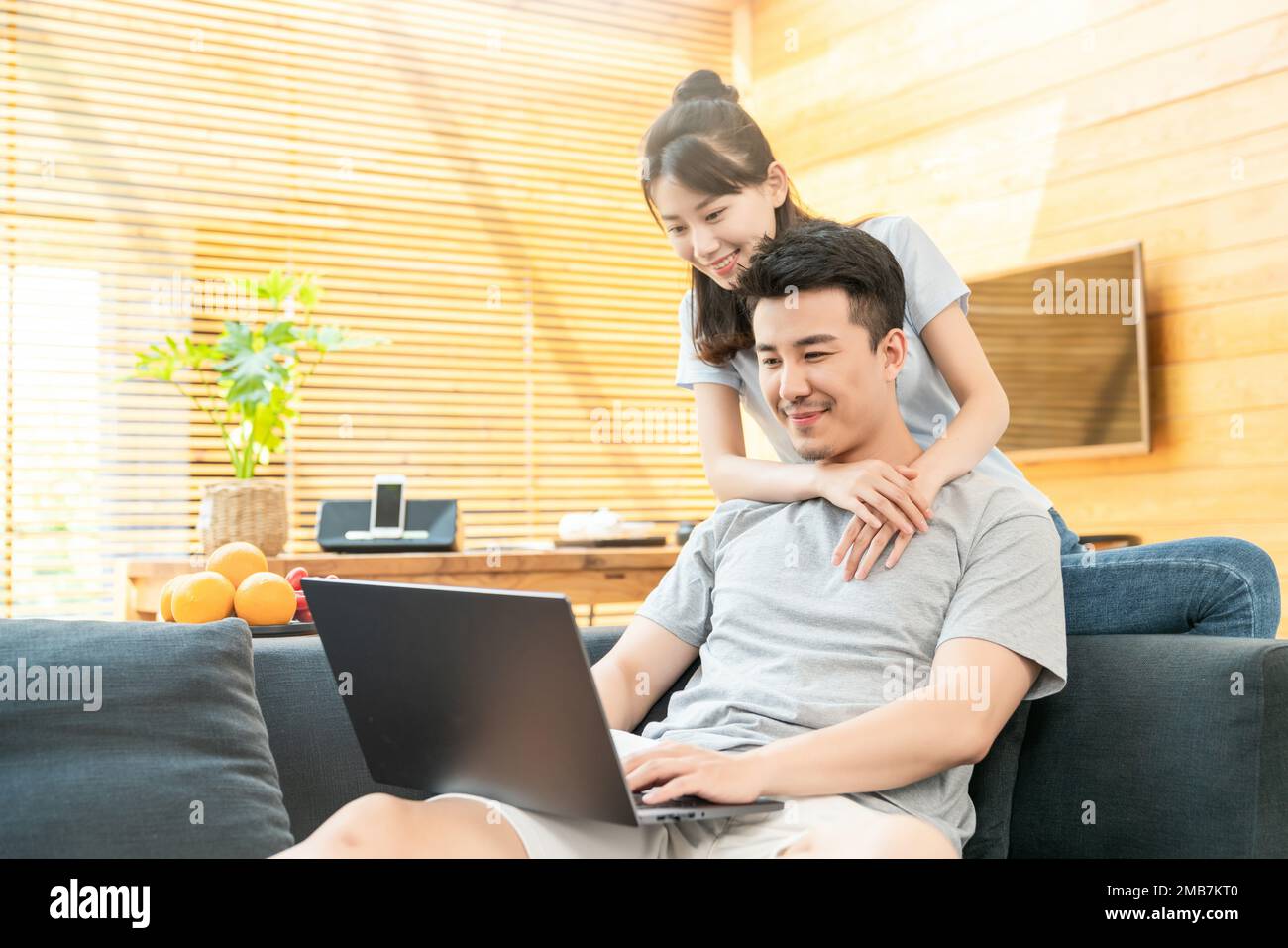 Couple Using One Computer Young couples to use a computer on the sofa Stock Photo - Alamy