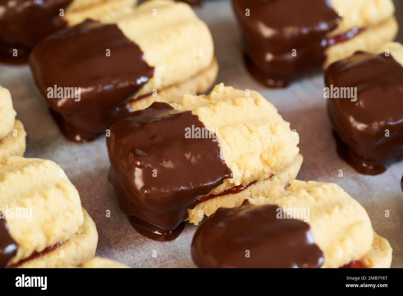 Closeup of homemade traditional Christmas cookies filled with strawberry marmalade and dipped in chocolate Stock Photo