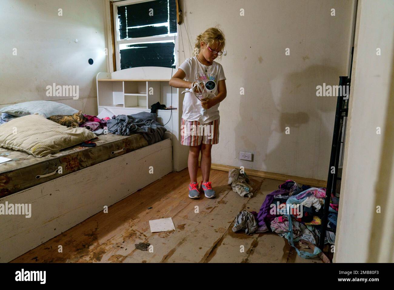 Harlee Holmes, 8, cleans out her room as her family is forced to leave