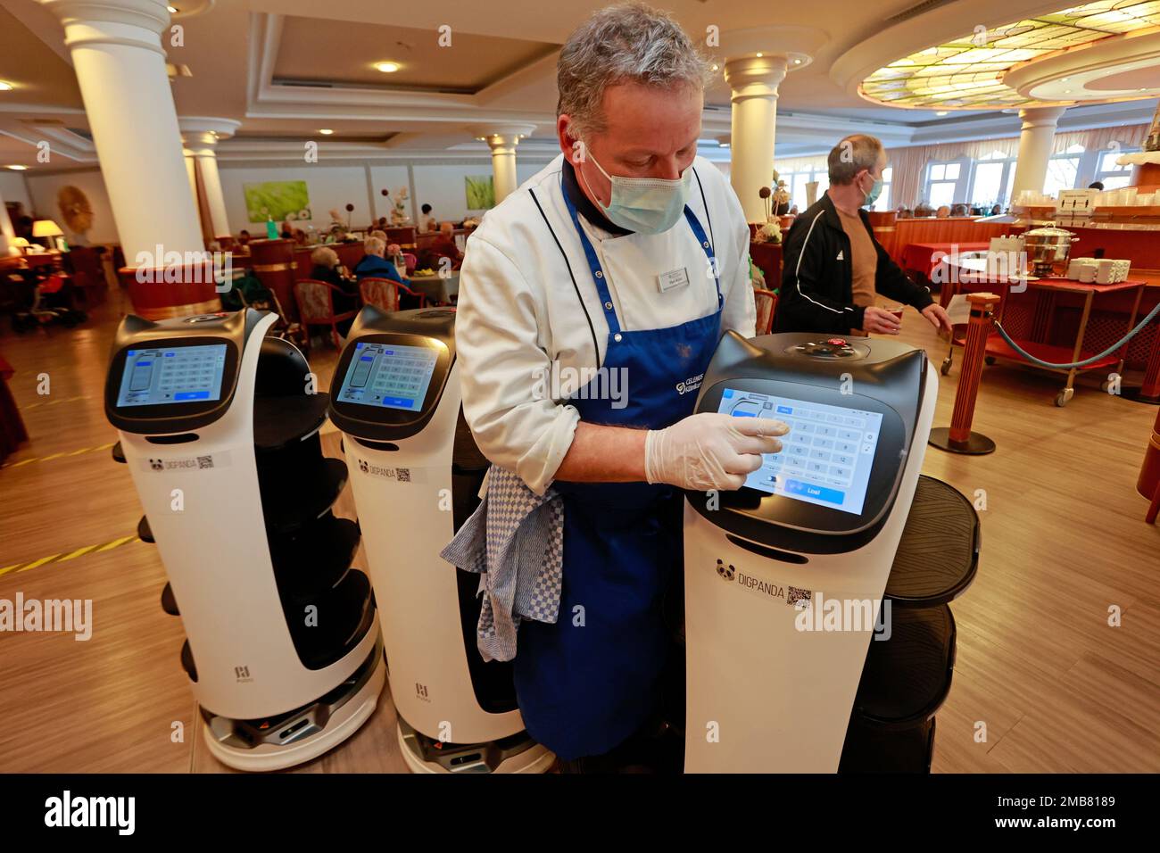 Blankenburg, Germany. 20th Jan, 2023. A robot cat is programmed by chef Uwe Müller in the dining room of the Celenus Teufelsbad-Fachklinik in Blankenburg. The BellaBot robots deliver the food placed on the shelves by the staff directly to the patients' table. They are designed to relieve staff of a great deal of physical work. According to its own information, the Teufelsbad Fachklinik in Blankenburg is currently the first clinic to test the use of the robots. Credit: Matthias Bein/dpa/Alamy Live News Stock Photo