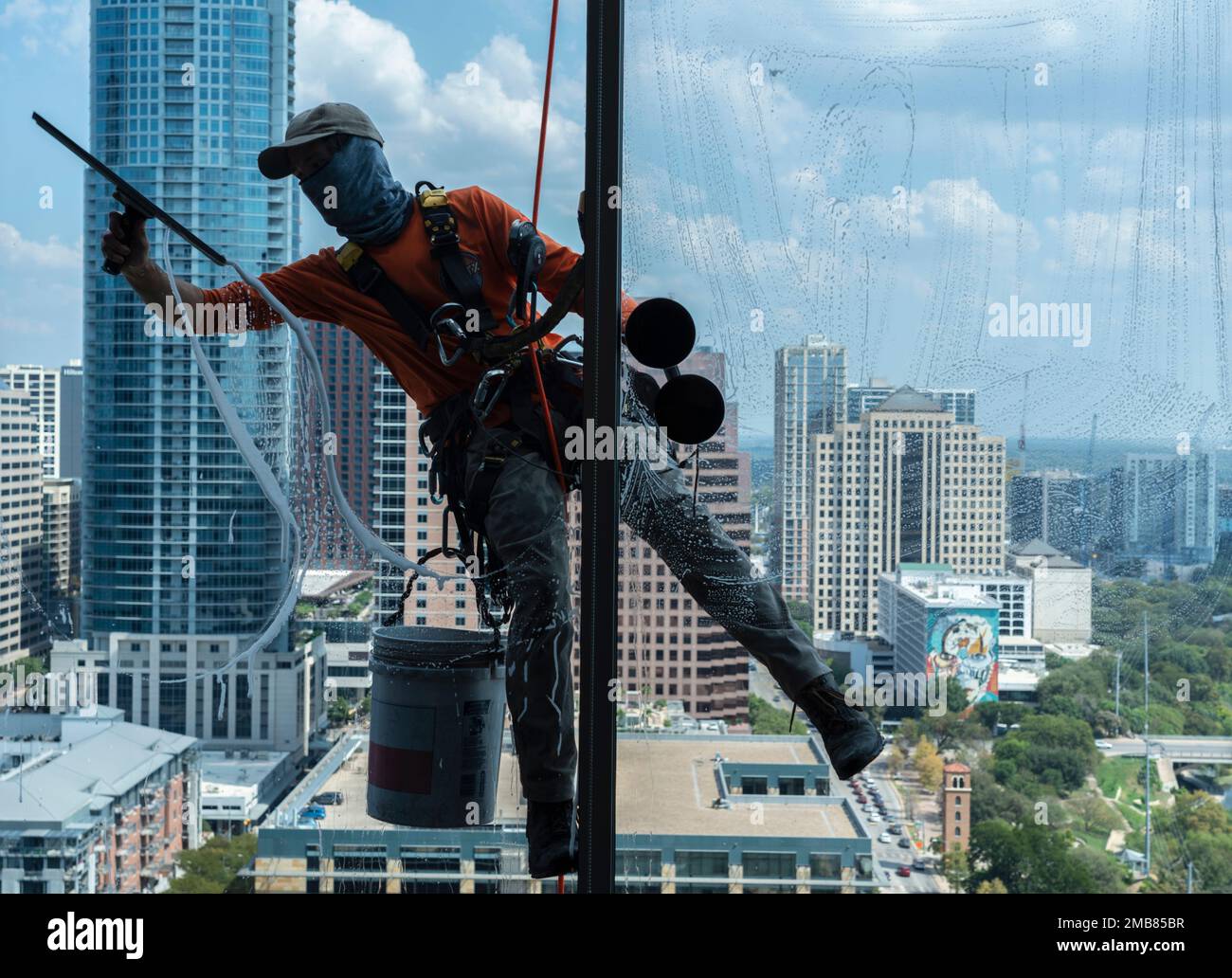 Window washer high on apartment building with Austin CIty Skyline. Stock Photo