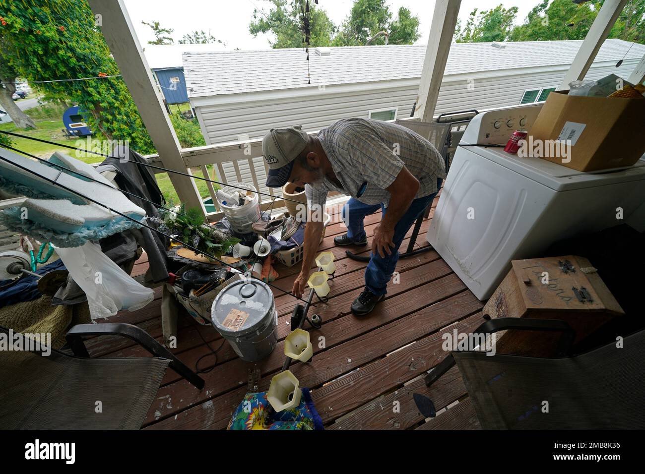 Lester Naquin clears room to sit on the porch of his home that was