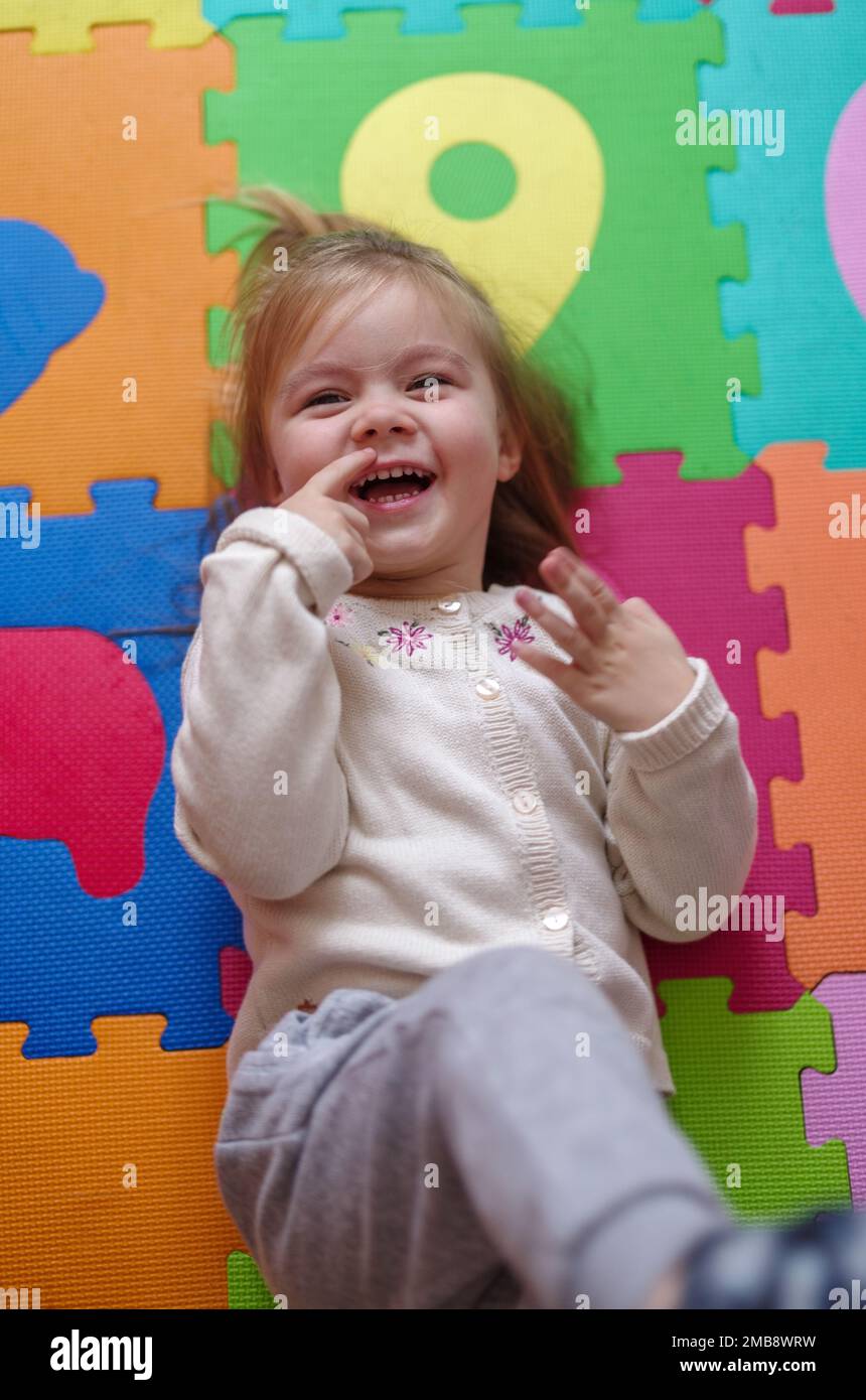 Happy Caucasian girl lying on puzzle mat Stock Photo - Alamy