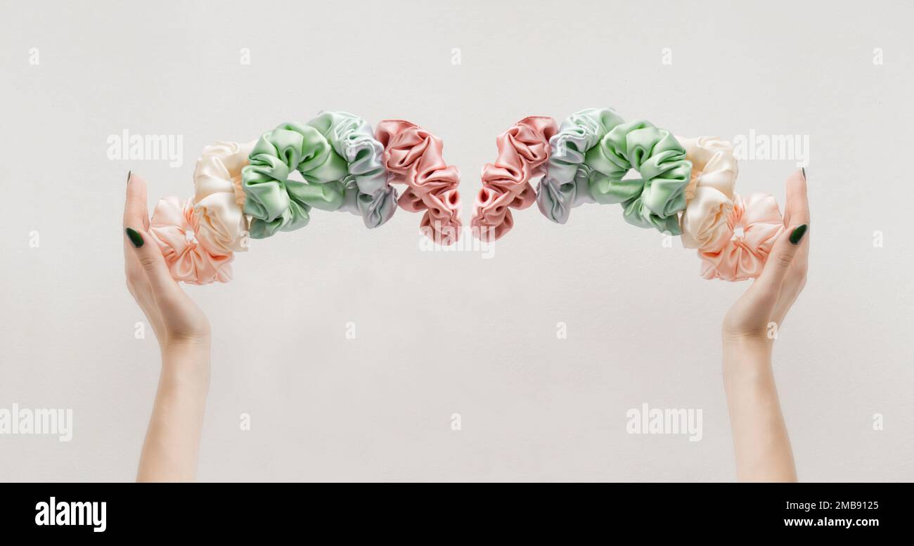 womas hands holding colorful scrunchies like crown on white banner. Elastic HairBands levitation Stock Photo
