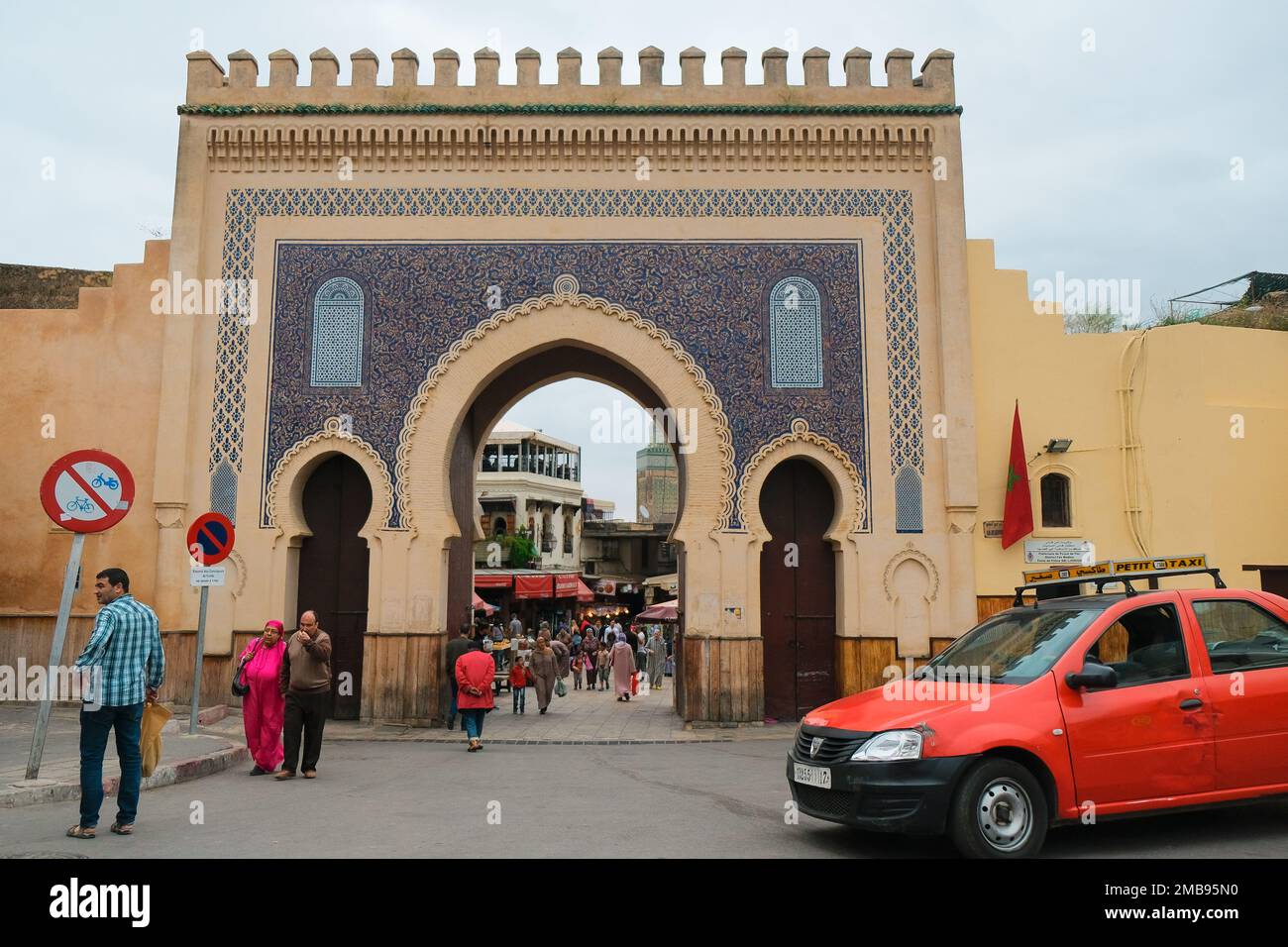 Fez, Morocco - grand city gate Bab Bou Jeloud in Fes el Bali. Monumental French entrance. Red petit taxi parked outside the ancient medina. Fes landmark. Stock Photo