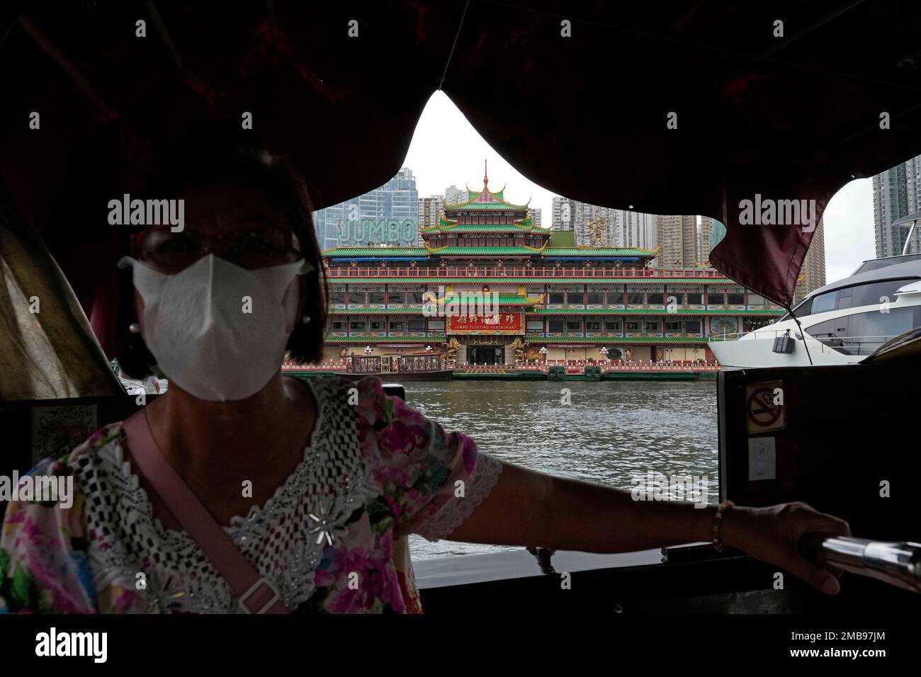 A woman sails a boat by the last Chinese imperial-style Hong Kong Jumbo  Floating Restaurant, which was featured in many local and international  movies over the years, in Hong Kong, Monday, June