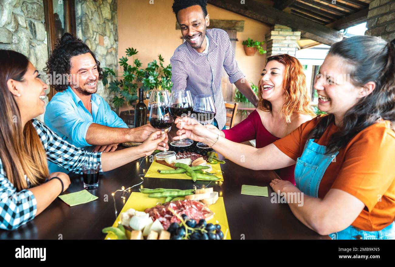 Happy friends having fun drinking at farm house garden patio - Life style concept with young people enjoying harvest time together - Red wine tasting Stock Photo