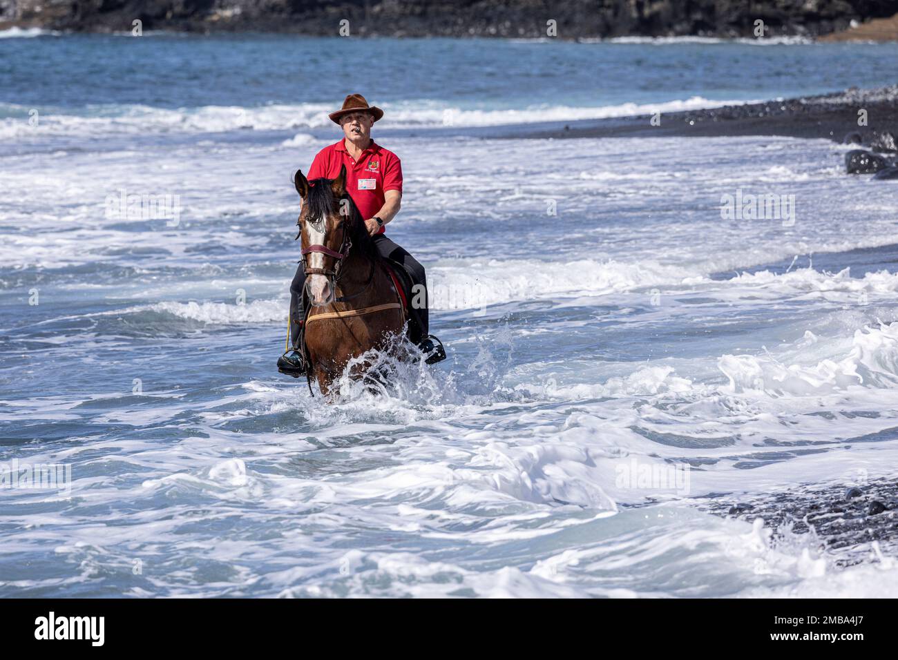 Costa Adeje, Tenerife, Canary Islands, 20 January 2023. Riders take their mounts into the sea at Playa Enramada beach during the fiesta of San Sebastian which returns for the first time since 2020 due to the covid pandemic restrictions. The annual fiesta in La Caleta on the Costa Adeje is enjoyed by locals and tourists who gather to see the many horses that come to bathe in the sea at the Playa Enramada beach. Credit: Phil Crean A/Alamy Live News Stock Photo