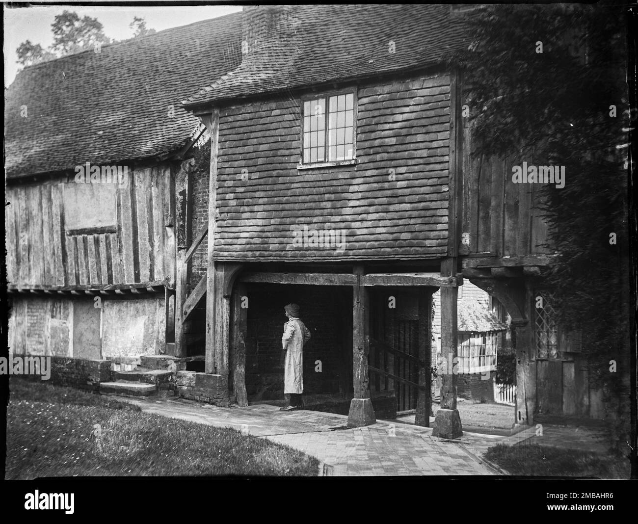 Leicester Square, Penshurst, Sevenoaks, Kent, 1911. A view from the north-west showing a figure standing under the archway in Leicester Square, Penshurst, looking at one of the timbers of the lych gate leading to St John's Church. Stock Photo