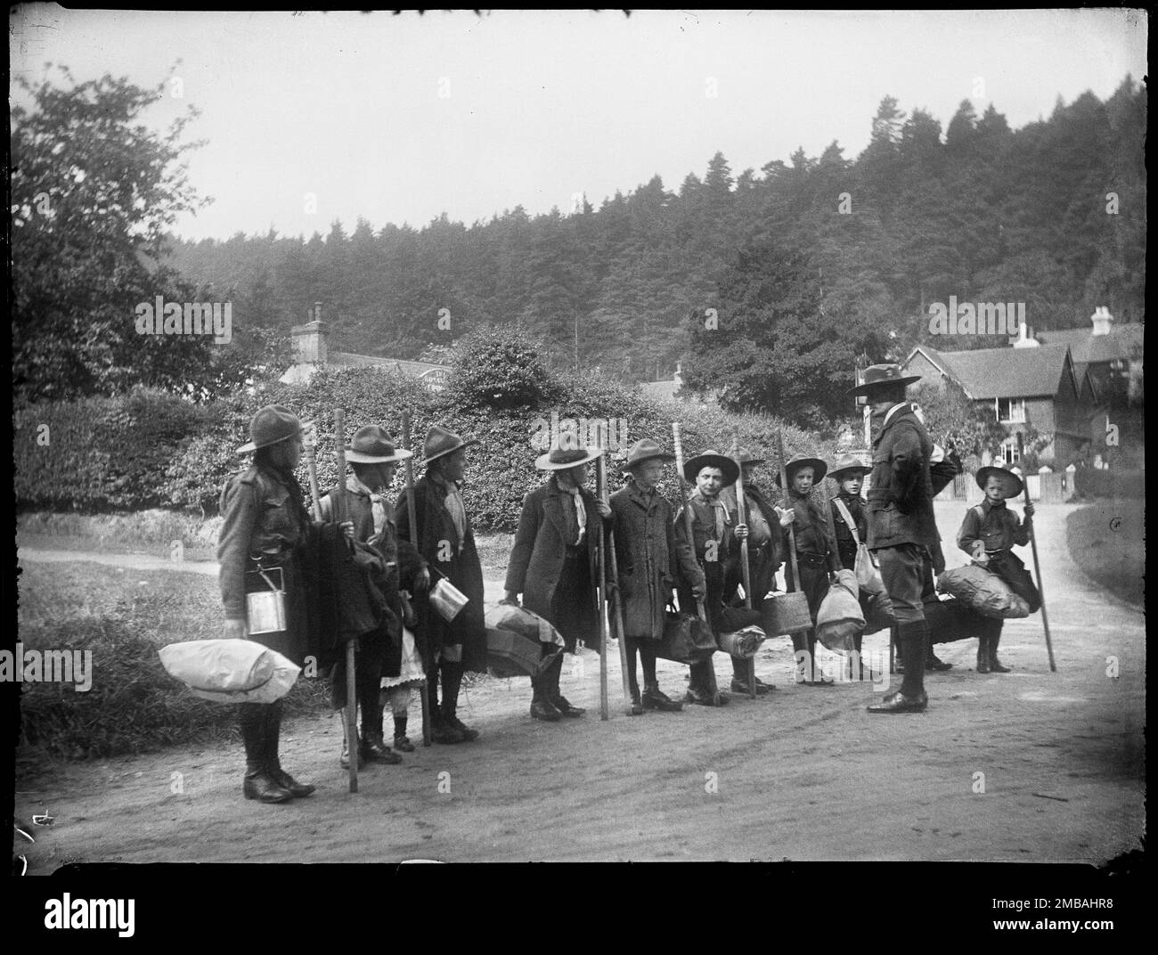Holmbury St Mary, Shere, Guildford, Surrey, 1912. A line of boy scouts and their scout master standing on a road in Holmbury St Mary. The scouts are carrying scout staffs and bedrolls for a camping or pioneering trip. Stock Photo