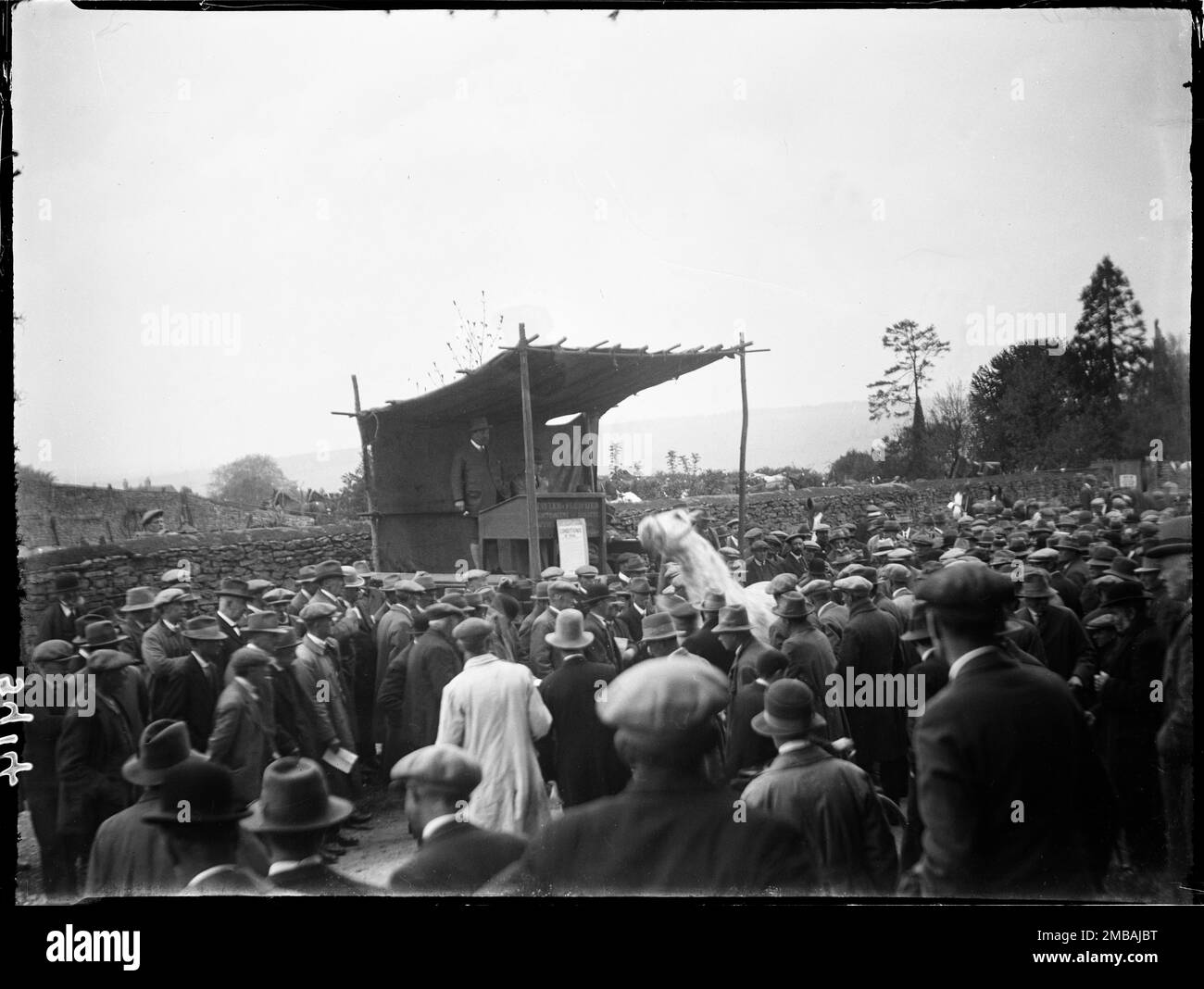 Stow-on-the-Wold, Cotswold, Gloucestershire, 1928. Looking over a crowd of men towards an auctioneers rostrum at the Stow Horse Fair, with a white horse at the centre of the crowd. The auctioneers on the rostrum are from Cotswold auctioneers and valuers Tayler &amp; Fletcher. Stock Photo