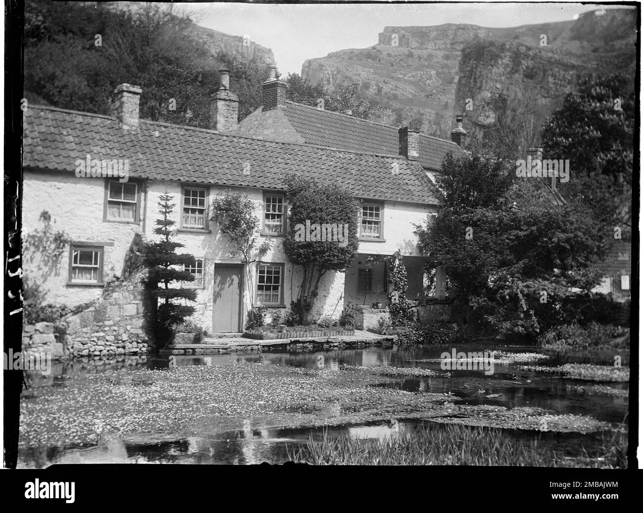 Mark Hole Cottage, The Cliffs, Cheddar, Sedgemoor, Somerset, 1907. A view across the mill pond near Cox's Mill towards the cottages at the head of the pond now known as Mark Hole Cottage. Mark Hole Cottage is a grade II listed building which was known as Cheddar Pottery when it was first designated in 1985. Stock Photo