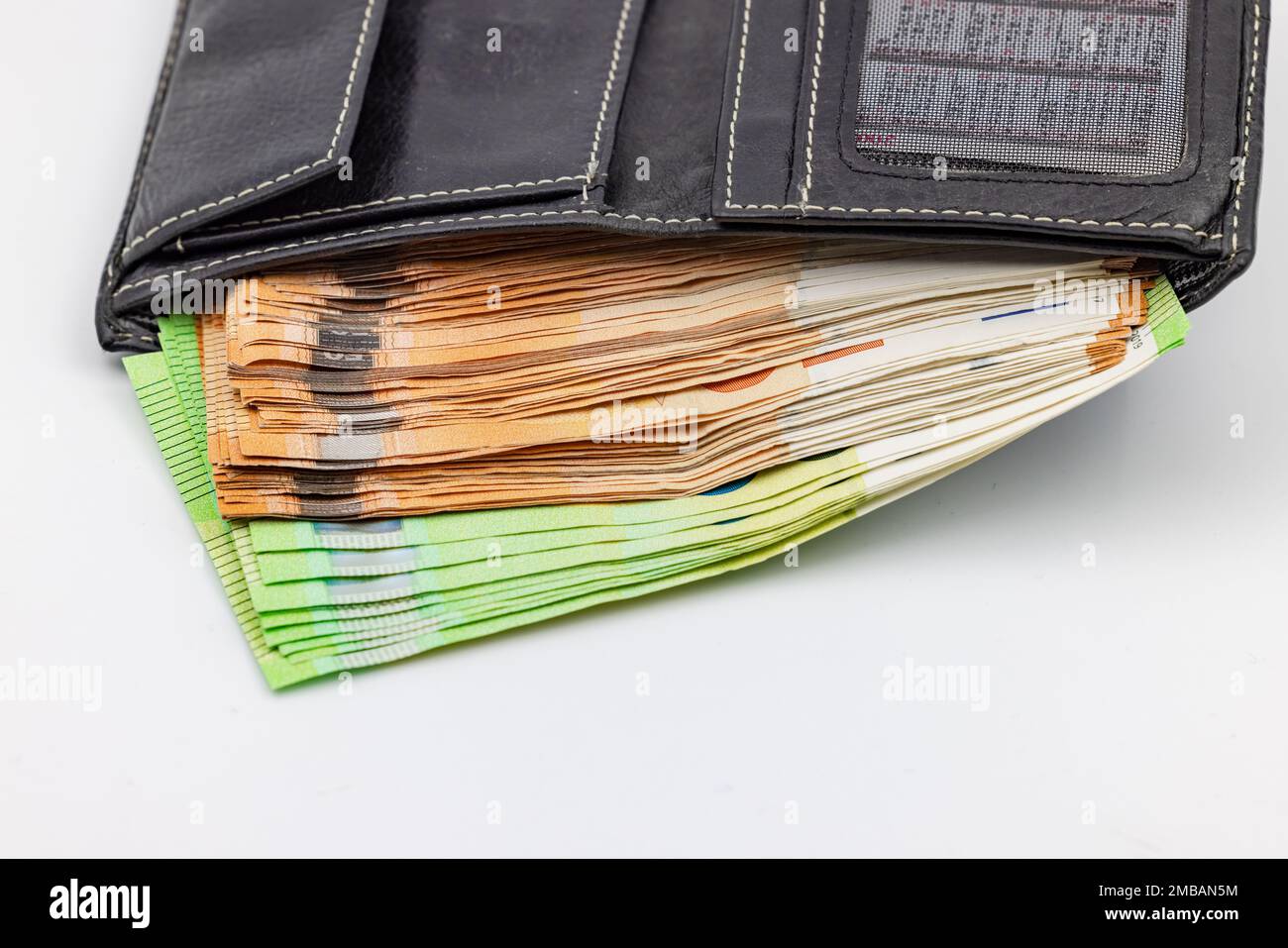 A black purse is overflowing with euro banknotes and banknotes Stock Photo