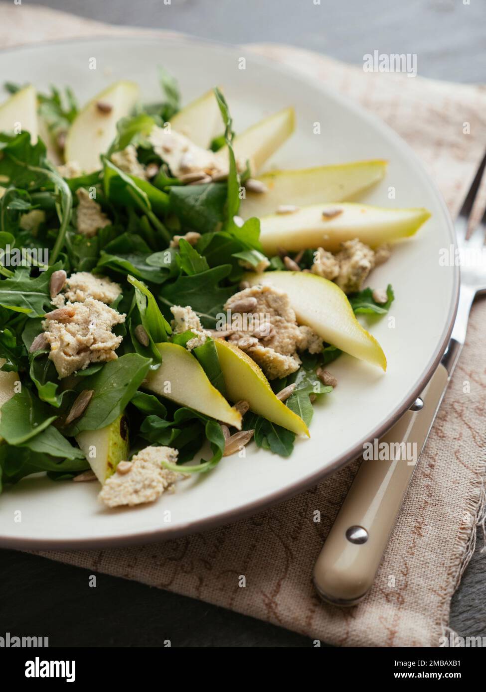 Plate with a pear and arugula salad with home made vegan feta cheese. Stock Photo