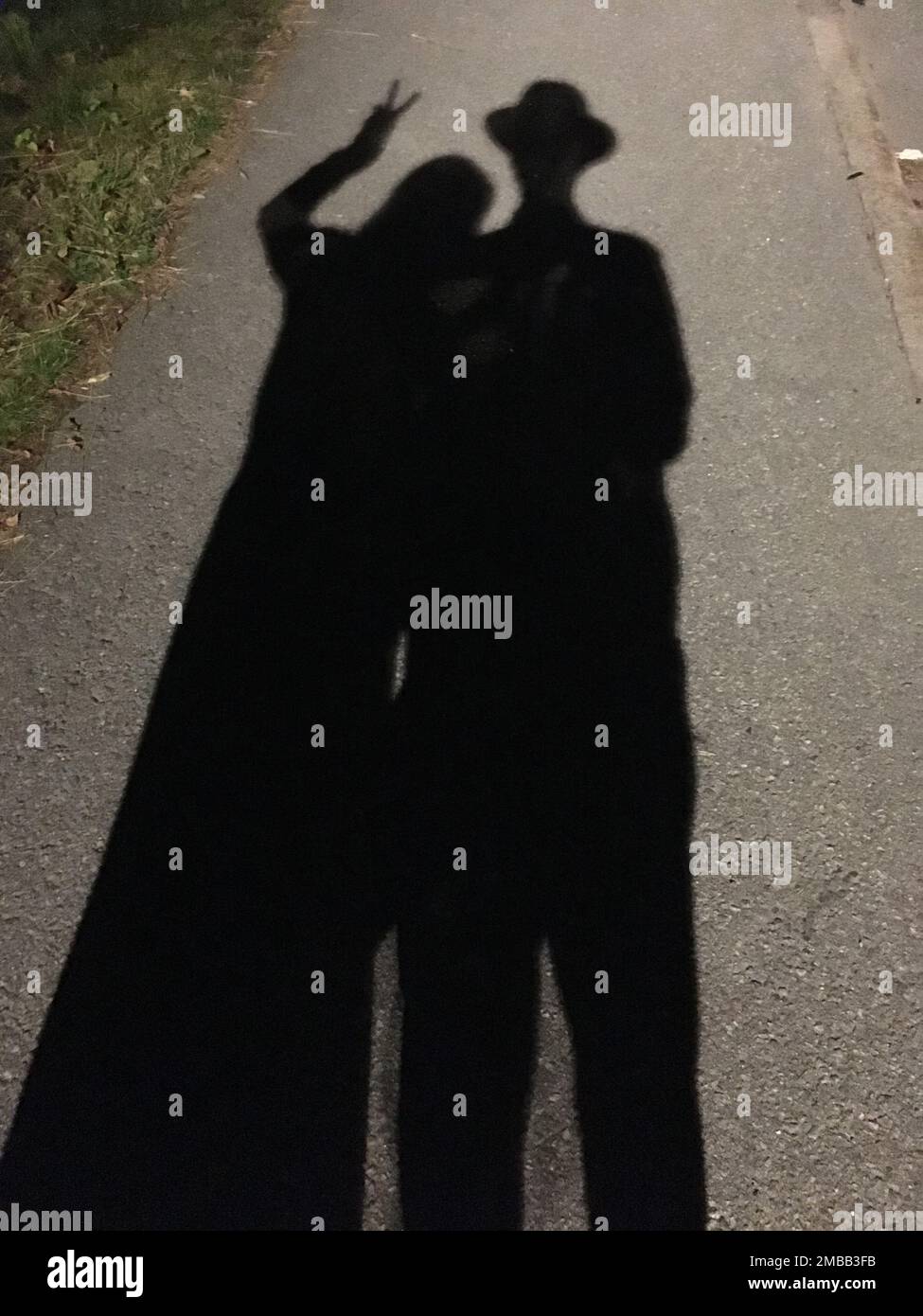 A vertical shot a shadow on the asphalt of a couple posing Stock Photo ...