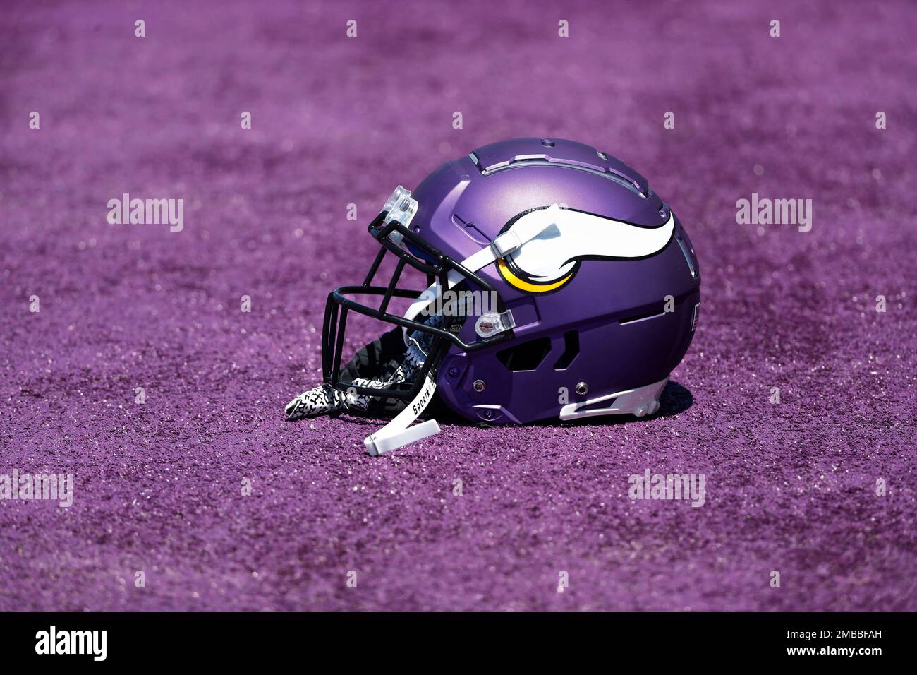 A Minnesota Vikings helmet rests on purple turf as players take