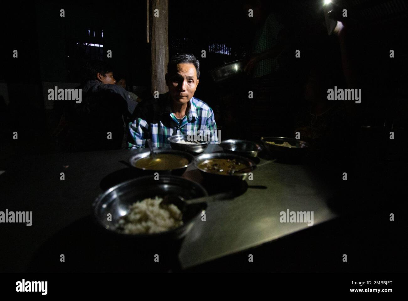 Myanmar Portrait During Power Outage - flash lights illuminate dinner in rural Myanmar Stock Photo
