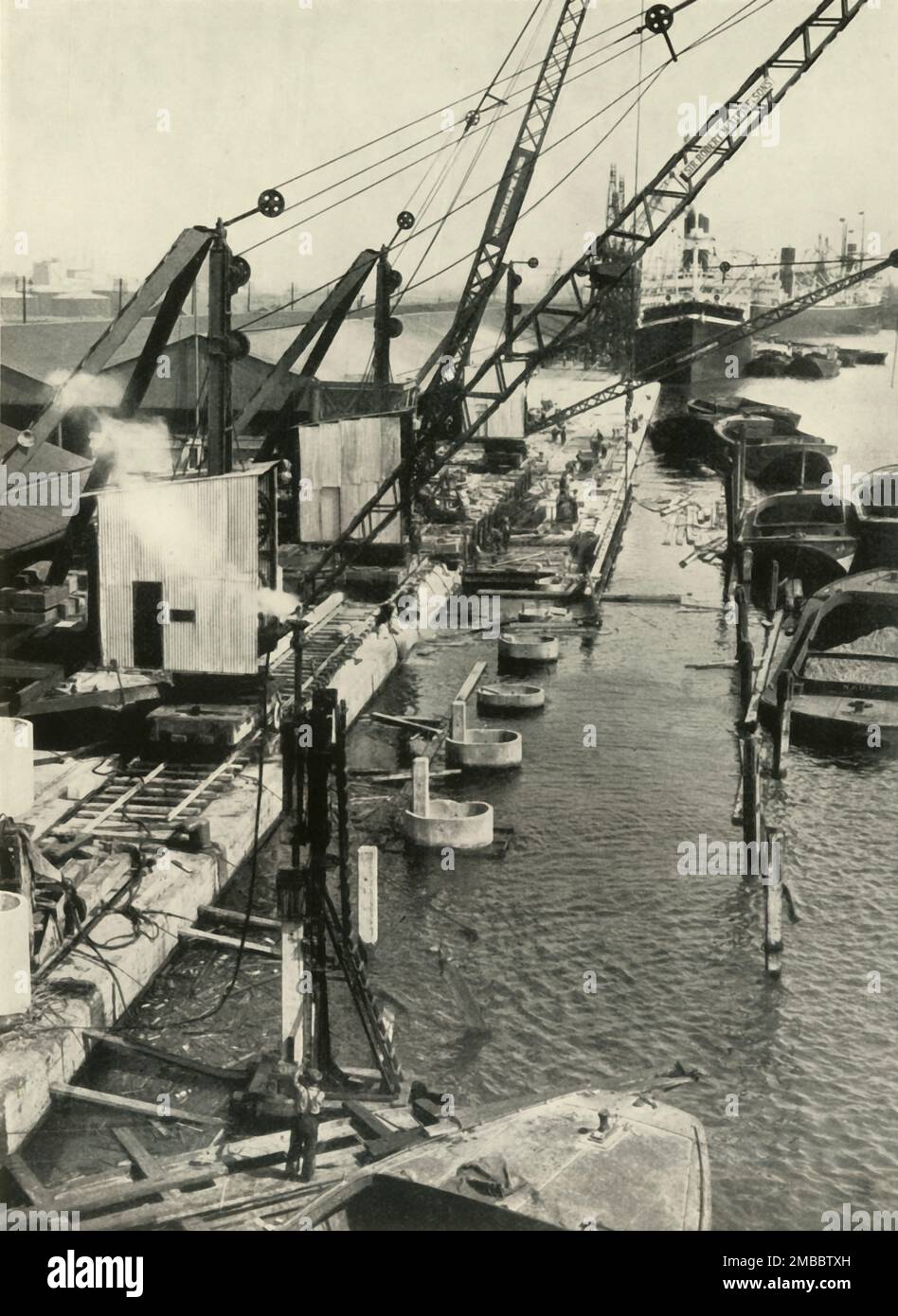 &quot;More New Quays (The Royal Albert Docks Will Obtain a Stretch Almost a Mile Long)&quot;', 1937. Cranes for unloading goods on the River Thames in London. From &quot;The Said Noble River&quot;, by Alan Bell. [The Port of London Authority, London, 1937] Stock Photo