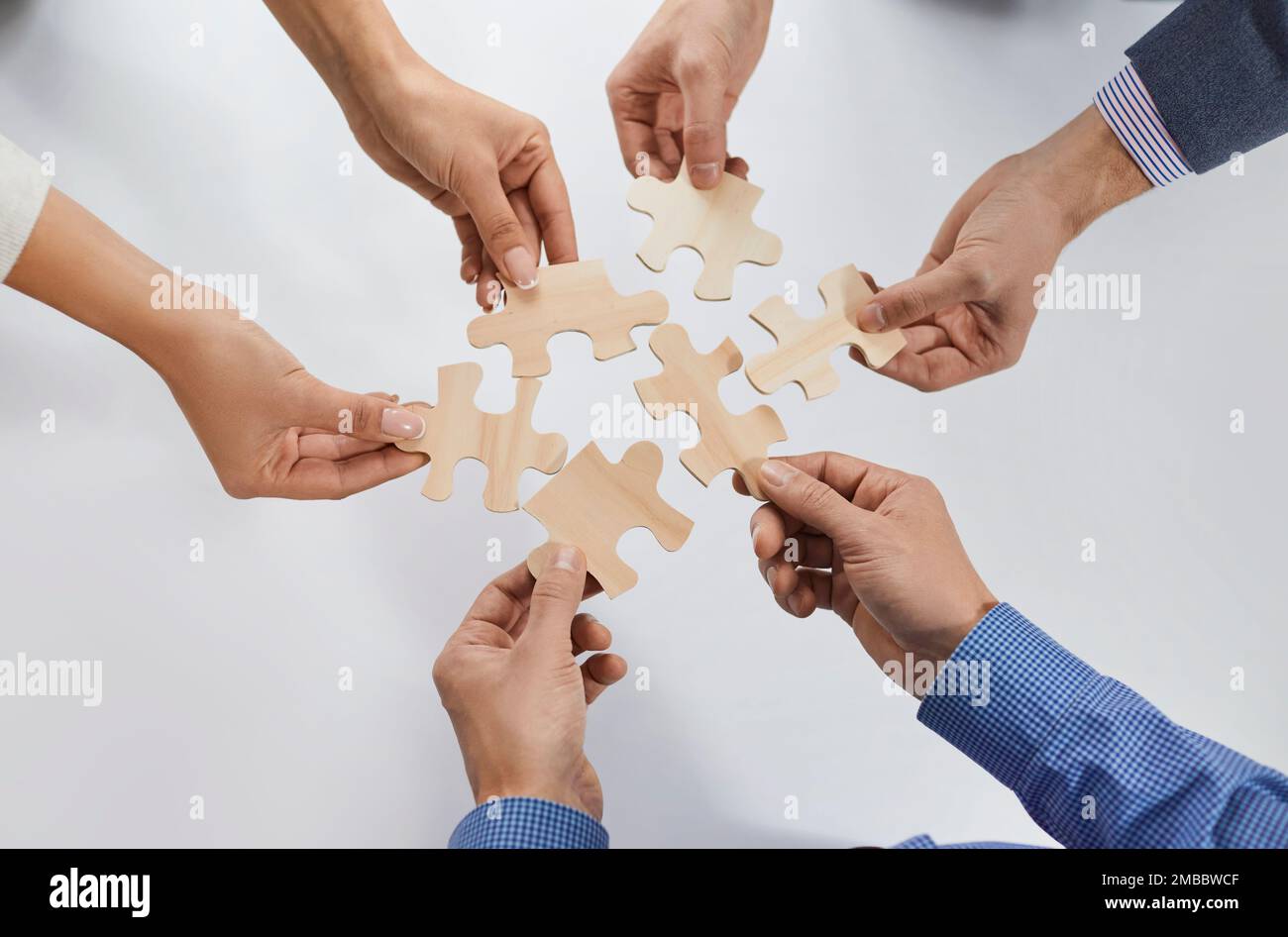Hands of group of business people assembling jigsaw puzzle. cooperation, teamwork support concept. Stock Photo