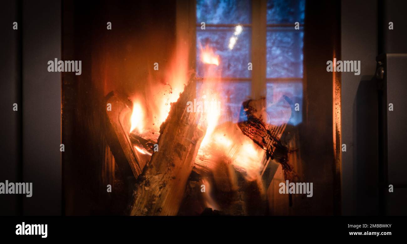 Fire in the fireplace behind a closed glass door. Stock Photo