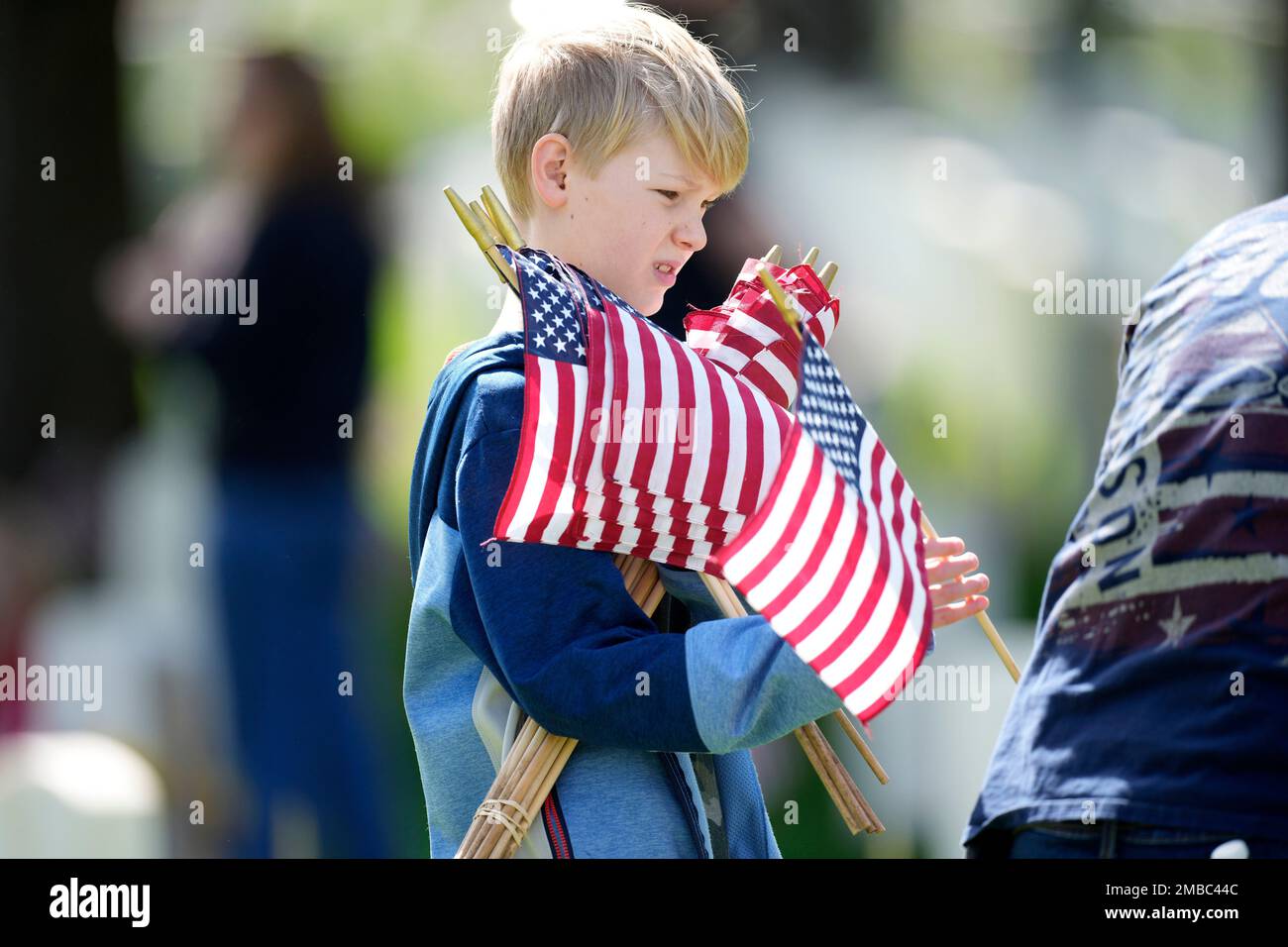 A young volunteer struggles to hold on to a an arm full of flags as he