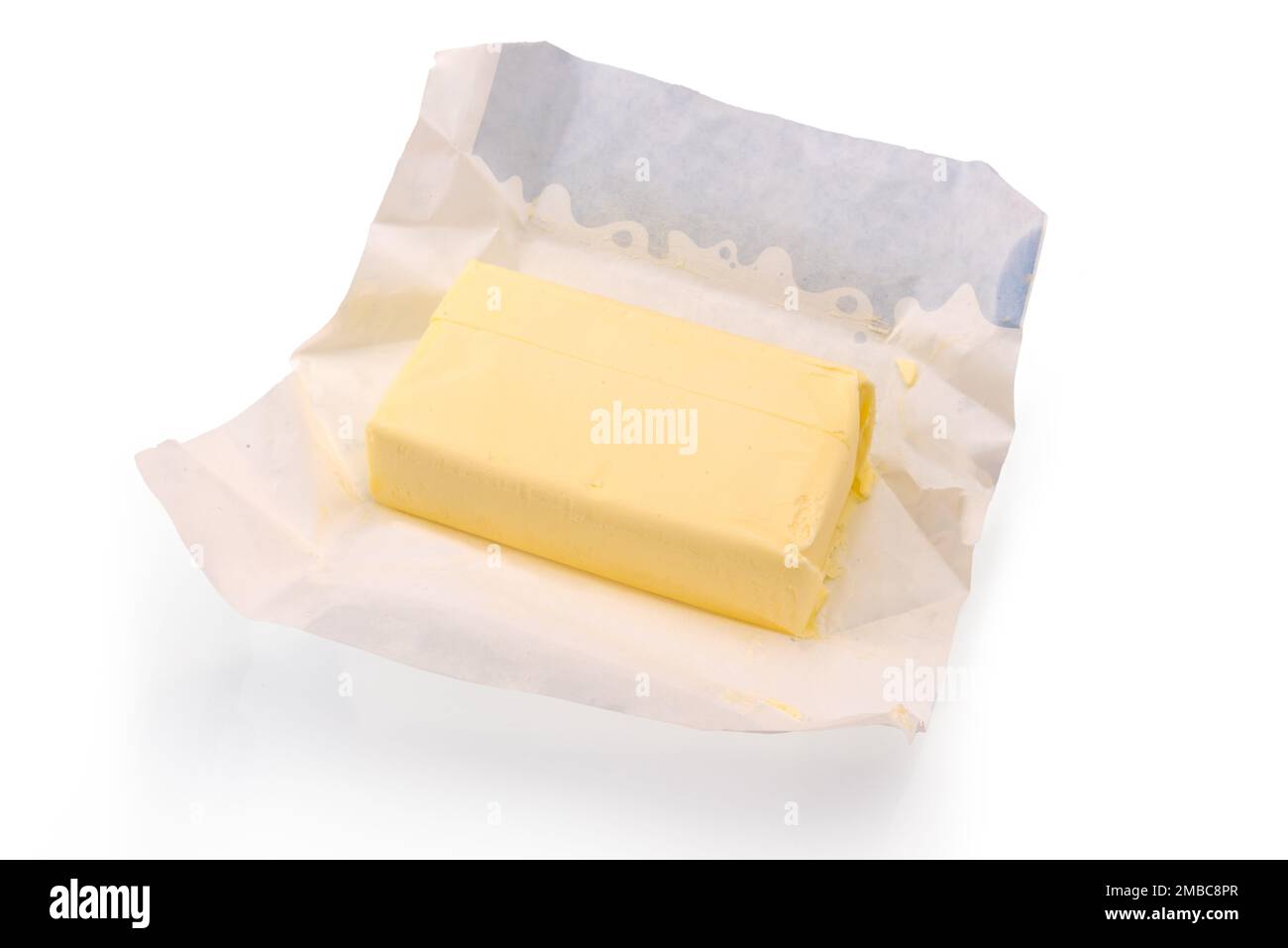 Unpacked stick of butter on wax paper from packaging, isolated on white, clipping path included Stock Photo
