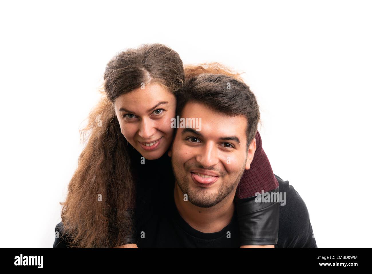 Cute young girlfriend hugging funny goofy boyfriend with tongue out close-up as love relationship concept isolated on white background Stock Photo