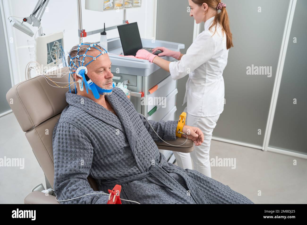 Man sits in medical chair with electrodes on his head Stock Photo