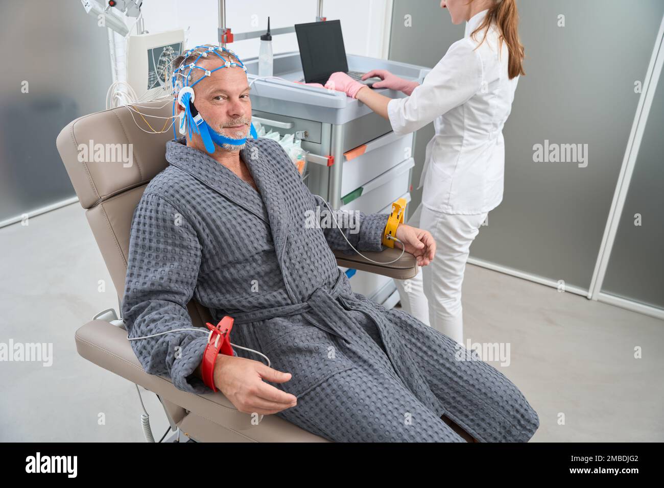 Elderly man sits in medical chair with electrodes on head Stock Photo