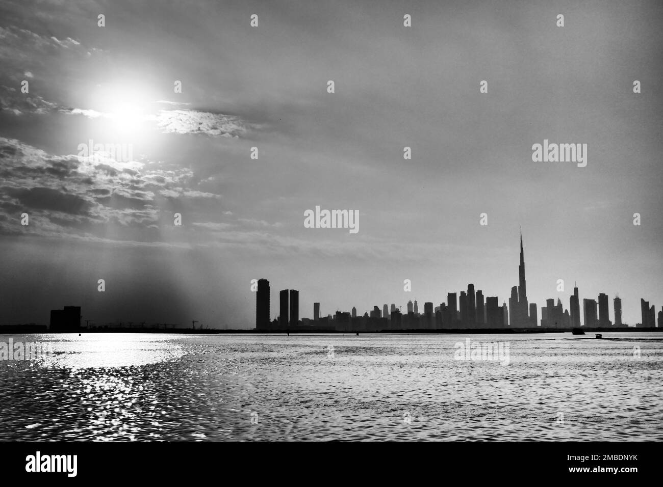 A grayscale view of the skyline of Dubai city from the sea at sunset