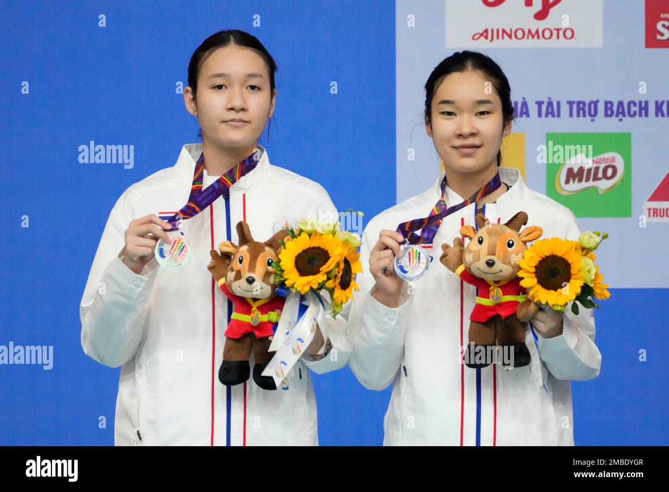 Thailands Benyapa Aimsaard, left, and Nuntakarn Aimsaard pose for photographers with their silver medals during the victory ceremony for womens doubles badminton at the 31st Southeast Asian Games (SEA Games) in Bac