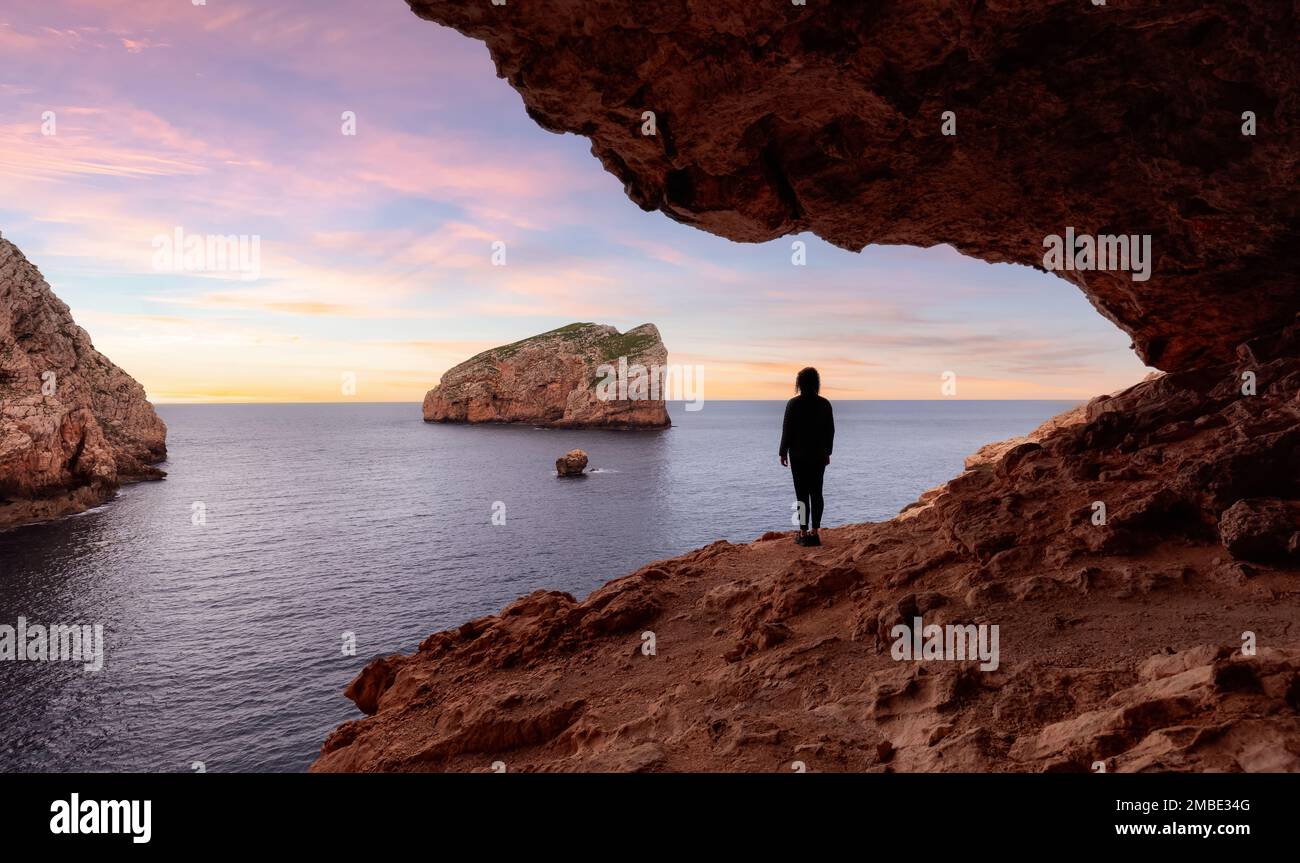 Adventurous Woman in a Cave on Rocky Coast with Cliffs on the Mediterranean Sea.  Stock Photo