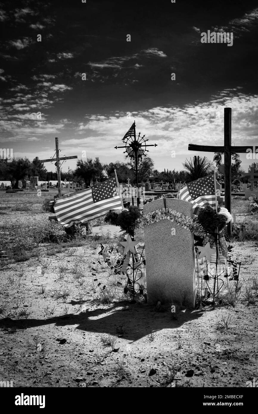 American flags wave in the breeze over a grave at a cemetery in Socorro, Texas. Stock Photo