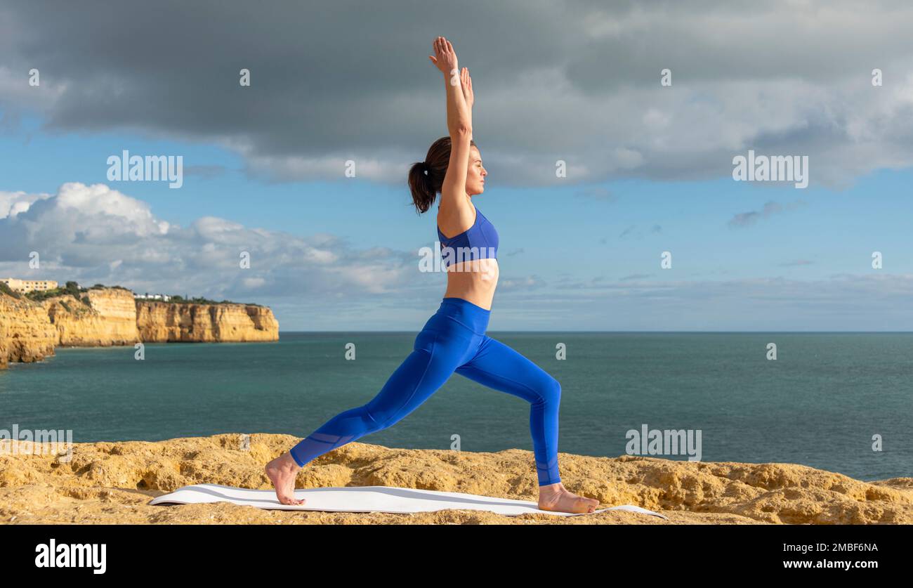 Fit woman kneeling on a yoga, exercise mat by the ocean Stock Photo Alamy