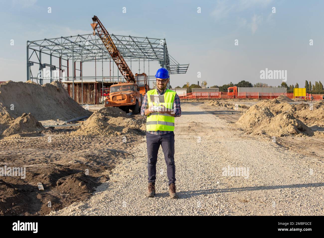 Engineer with helmet and vest operating with drone by remote control. Technology innovations in construction industry Stock Photo