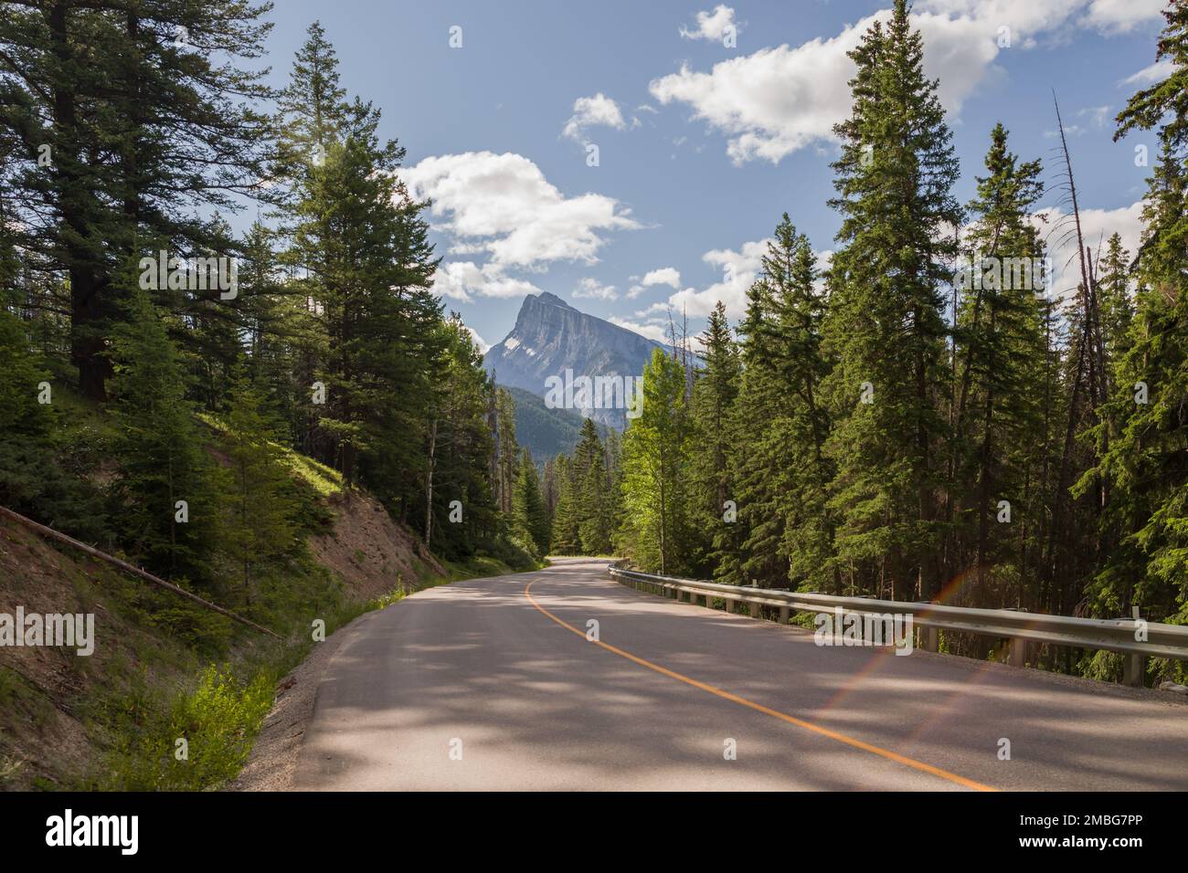 Mountain road. Travel background. Highway in mountains. Transportation. Landscape with rocks, sunny sky with clouds and beautiful asphalt road in the Stock Photo