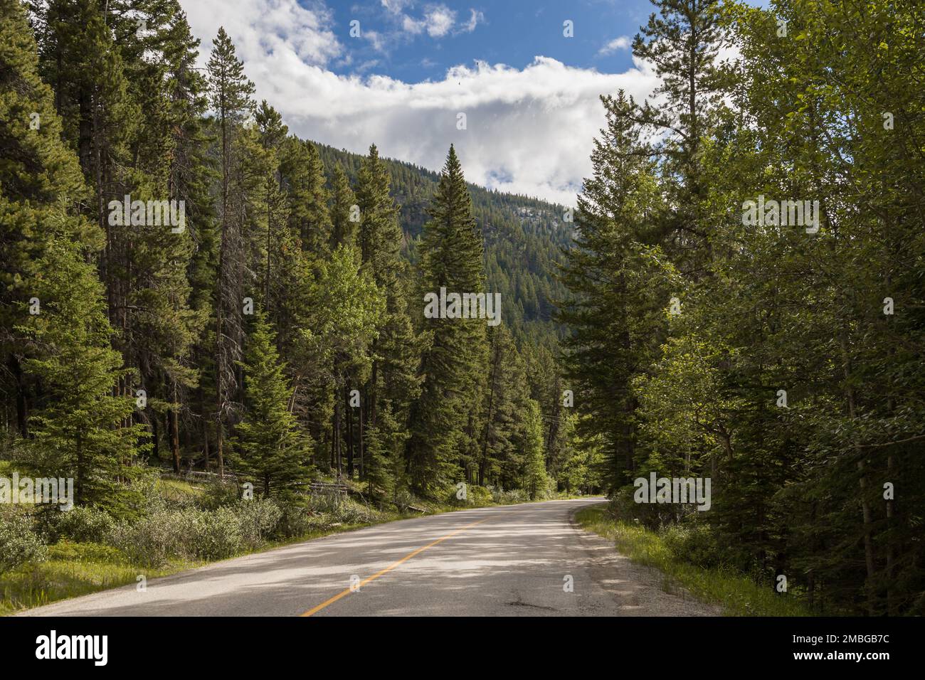 Mountain road. Travel background. Highway in mountains. Transportation. Landscape with rocks, sunny sky with clouds and beautiful asphalt road in the Stock Photo