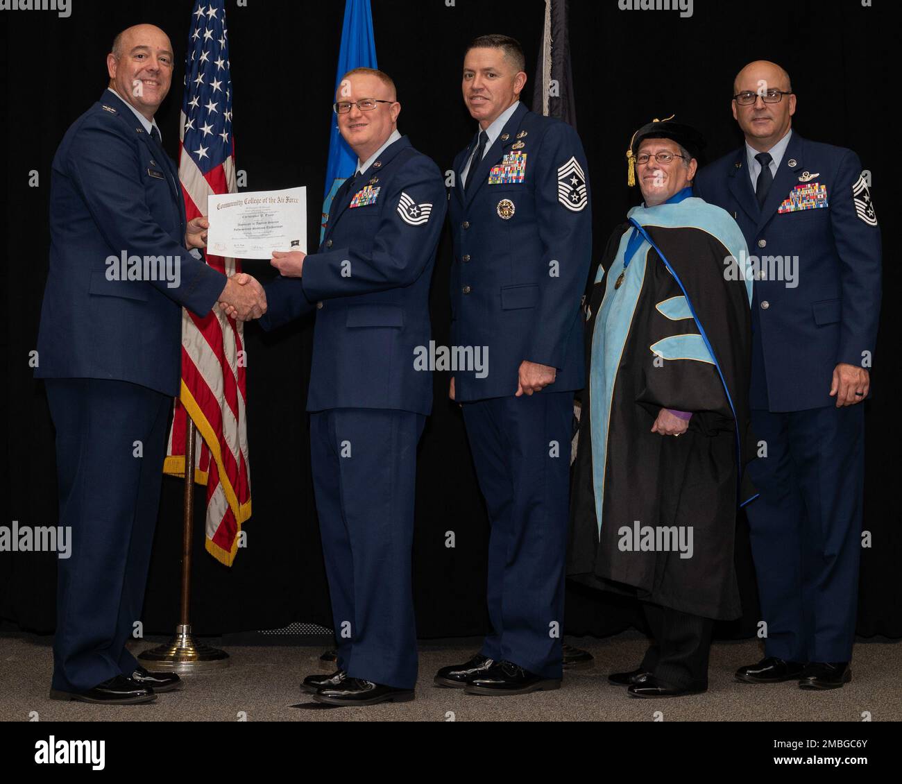 Col. Patrick Miller, 88th Air Base Wing and installation commander, presents Tech. Sgt. Christopher Tracy with his associate in applied science degree in information systems technology during the Community College of the Air Force graduation ceremony June 15, 2022, at the National Museum of the Air Force, Wright-Patterson Air Force Base, Ohio. With Miller were Jason Schaffer, 88 ABW command chief; Donald Ellwood, CCAF Education Services director; and Chief Master Sgt. James Fitch, Air Force Research Laboratory command chief; who gave the commencement address. Stock Photo