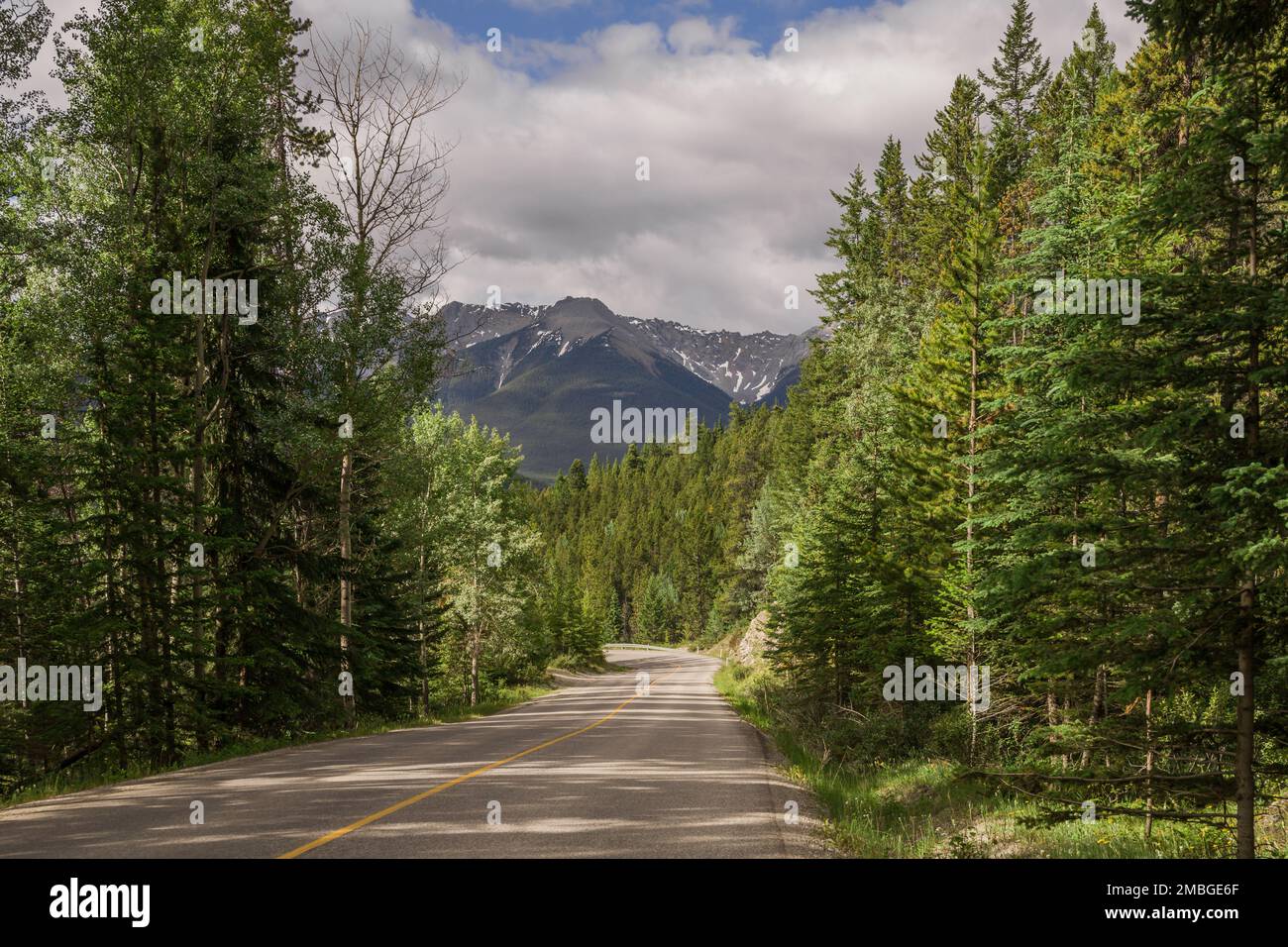 Mountain road. Travel background. Highway in mountains. Transportation. Landscape with rocks, sunny sky with clouds and beautiful asphalt road in the Stock Photo