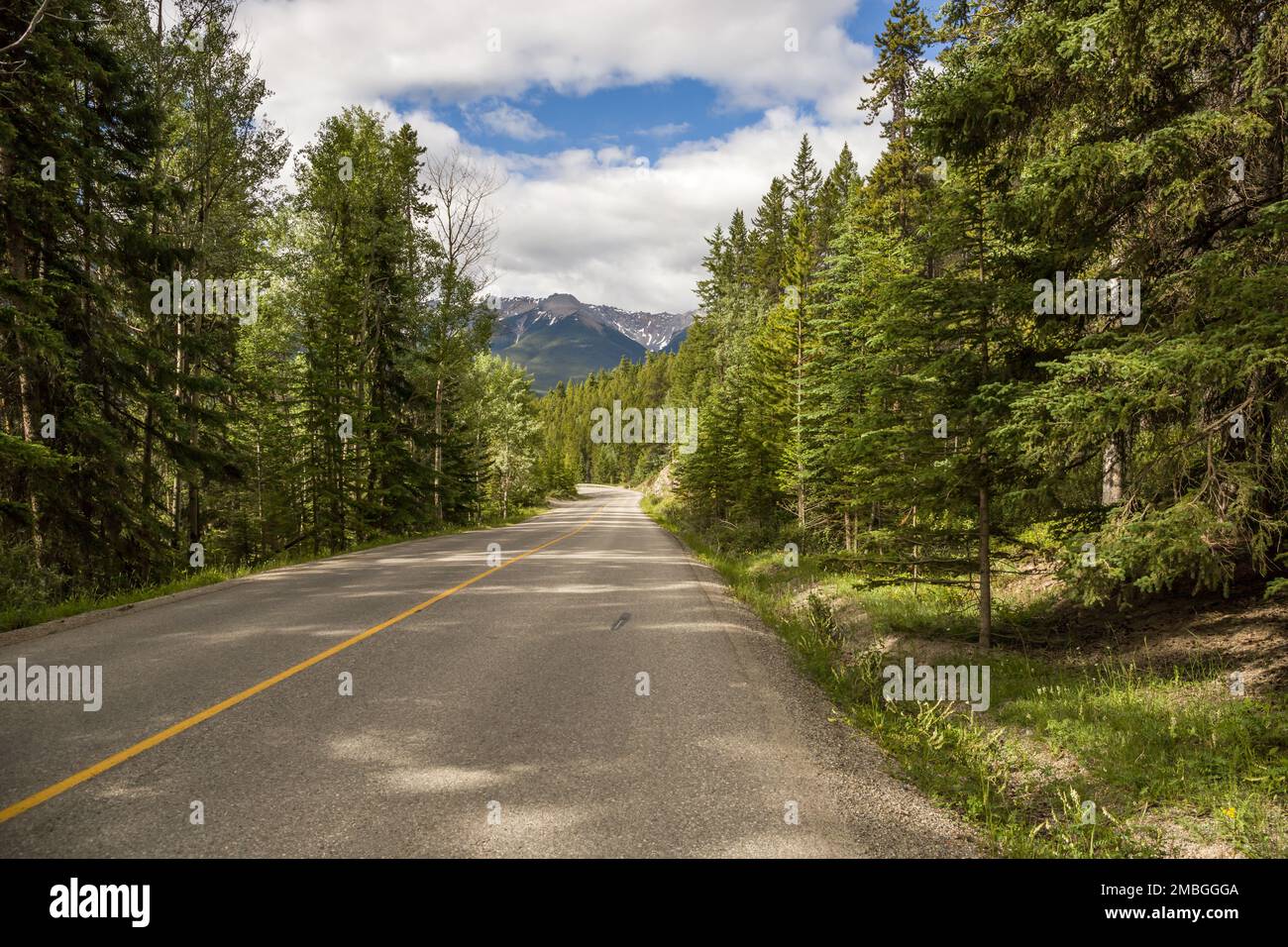 Mountain road. Travel background. Highway in mountains. Transportation. Landscape with rocks, sunny sky with clouds and beautiful asphalt road in the Stock Photo