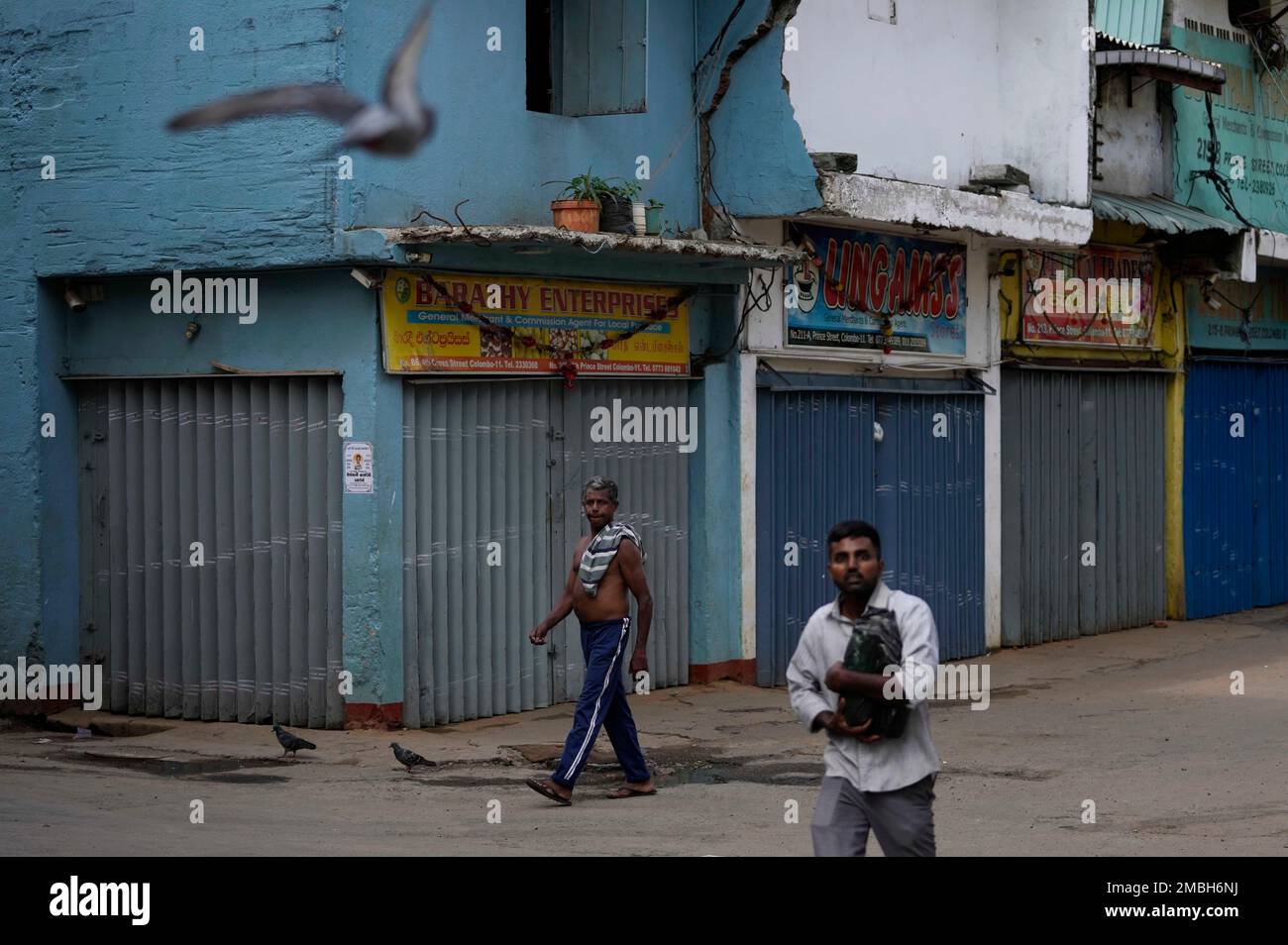 Sri Lankans walk on a deserted street at a wholesale market during