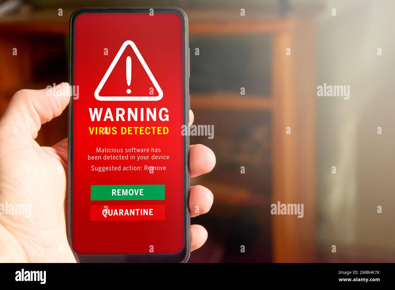 Male hand holding mobile phone with 'Virus detected' alert on the screen. Antivirus detecting malware, concept of mobile security and internet securit Stock Photo