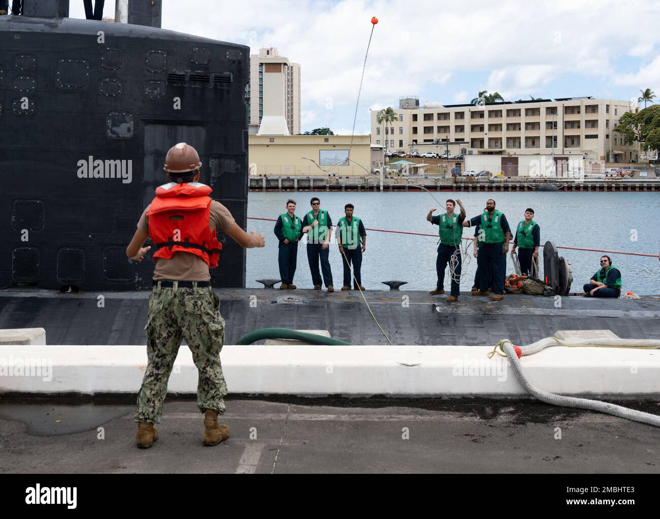 220616-N-MH811-1037 JOINT BASE PEARL HARBOR-HICKAM (June 16, 2022) -- Sailors aboard the Los Angeles-class fast-attack submarine USS Topeka (SSN 754) throw a heaving line to Sailors assigned to Los Angeles-class fast-attack submarine USS Charlotte (SSN 766), June 16, 2022. Topeka is capable of supporting various missions, including anti-submarine warfare, anti-surface ship warfare, strike warfare, and intelligence, surveillance, and reconnaissance. Stock Photo