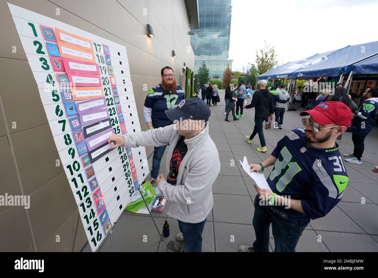 Ryan Tinnea, right, looks on as his brother, Brian Tinnea, center, updates their home-made NFL football draft board during an NFL football draft day party, Thursday, April 28, 2022, in Renton, Wash., near Seattle. (AP Photo/Ted S. Warren) Stock Photo