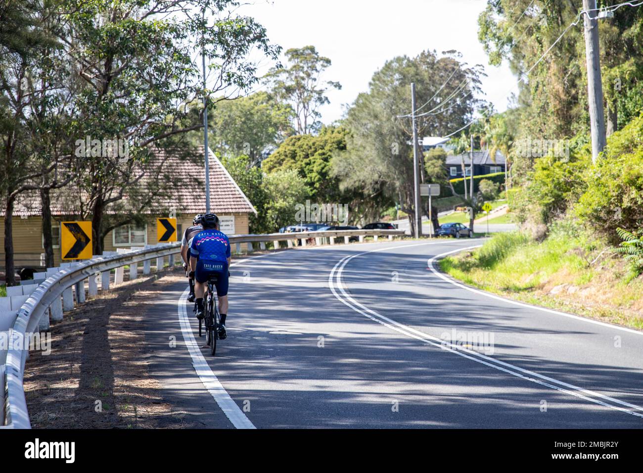 Two male cyclists riding along Pittwater road Church Point in Sydney