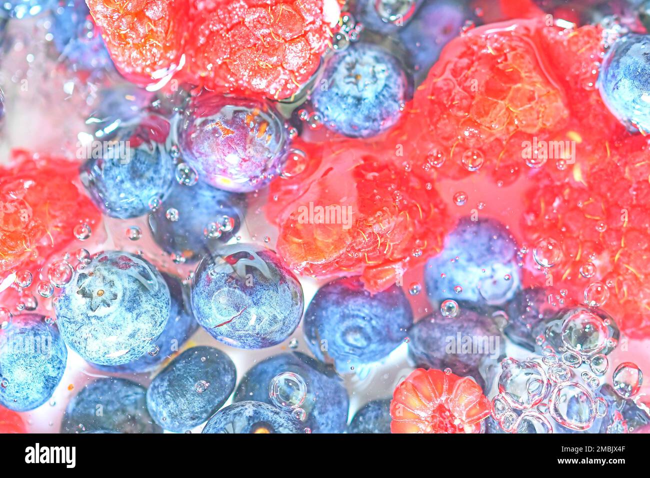 Blueberries and raspberries in liquid with bubbles. Colourful ripe